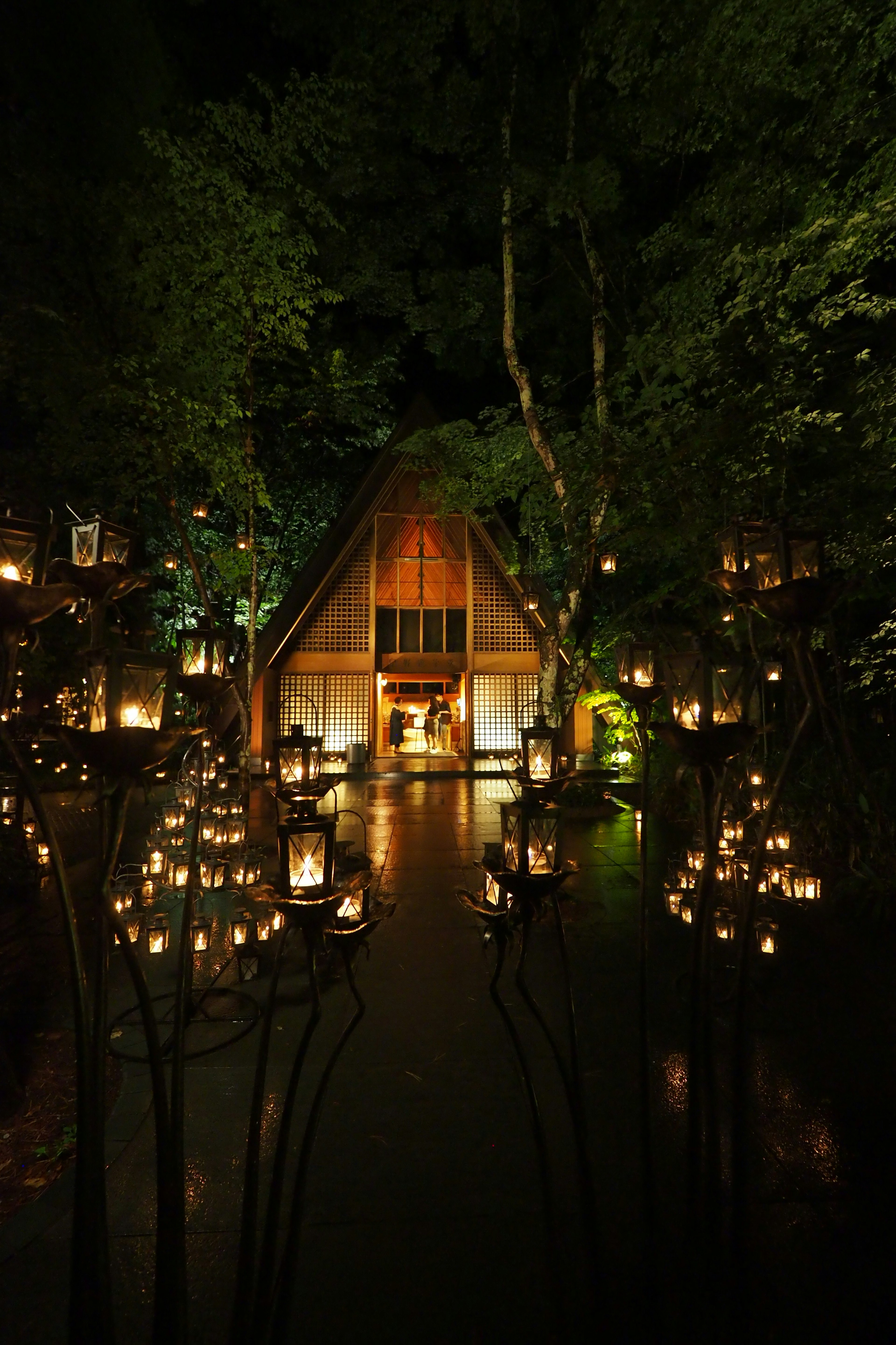 Vista nocturna de una cabaña iluminada por faroles en un bosque