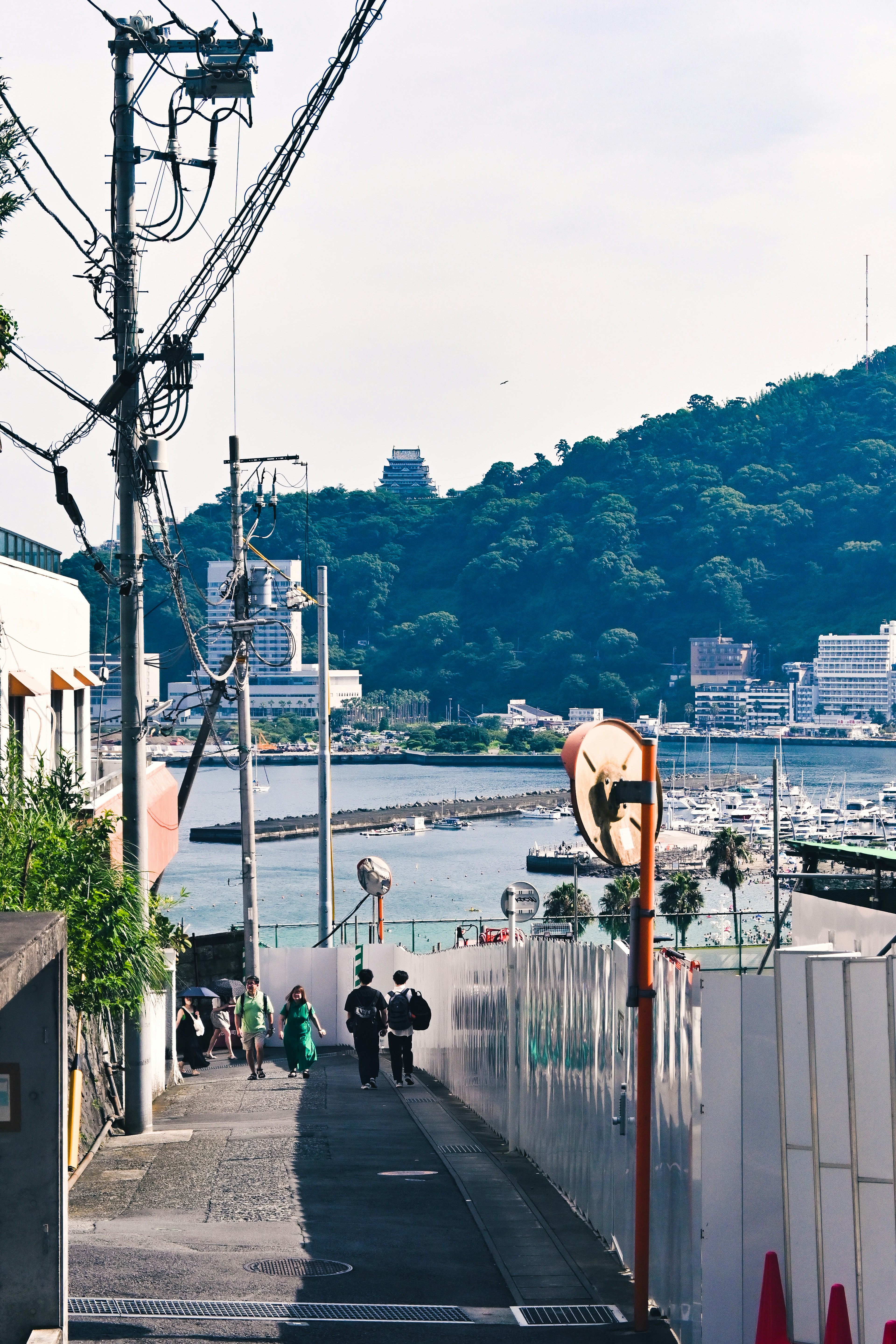 Path leading to the sea with two people walking and a mountain in the background