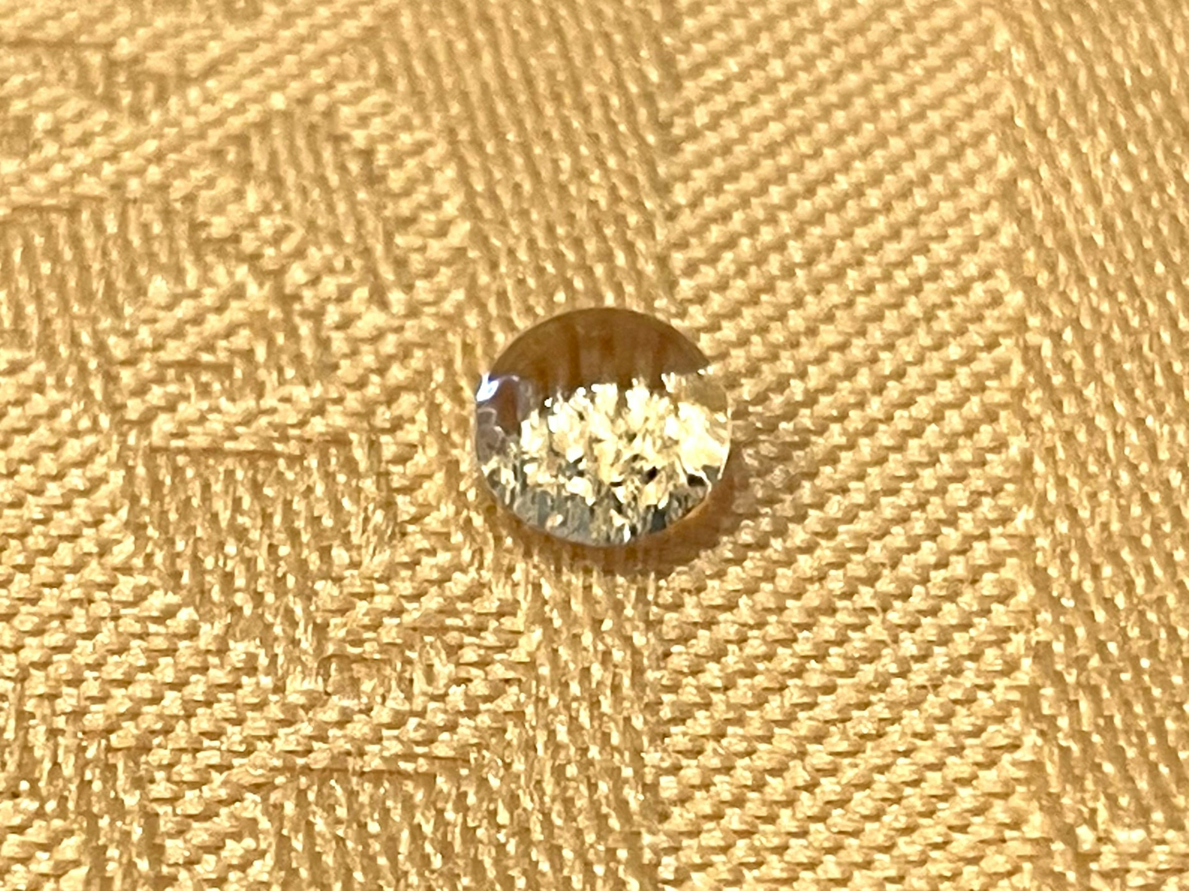 A transparent water droplet on a golden fabric surface