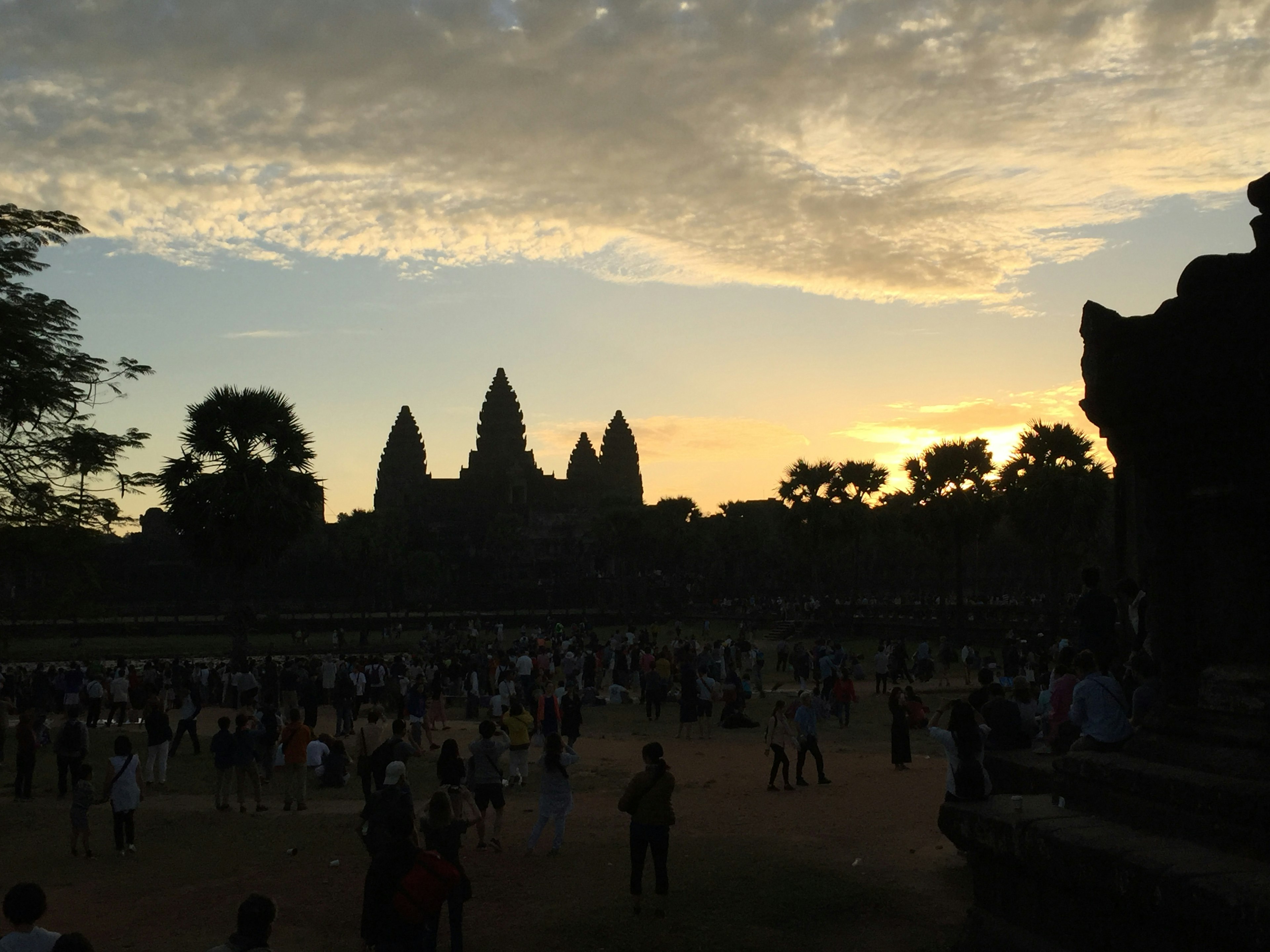 Silhouette Angkor Wat saat matahari terbenam dengan wisatawan