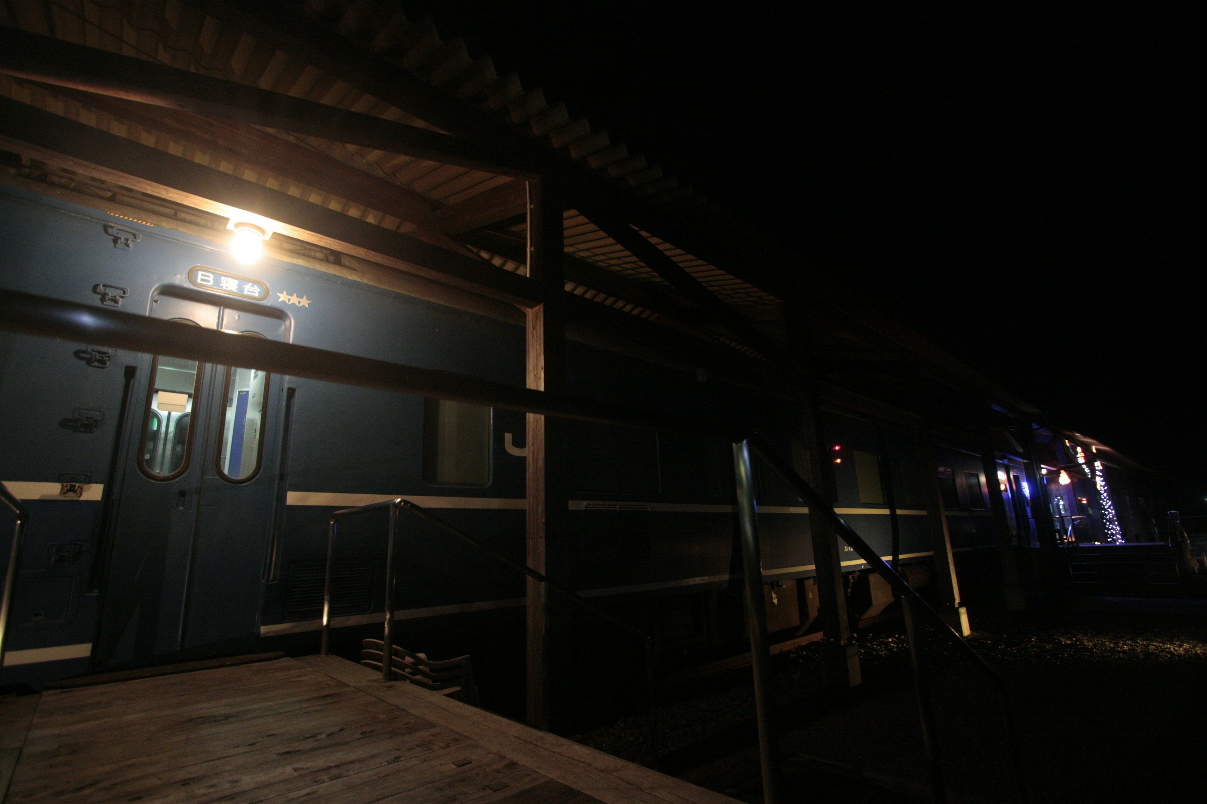 Side view of a blue train at night with lights