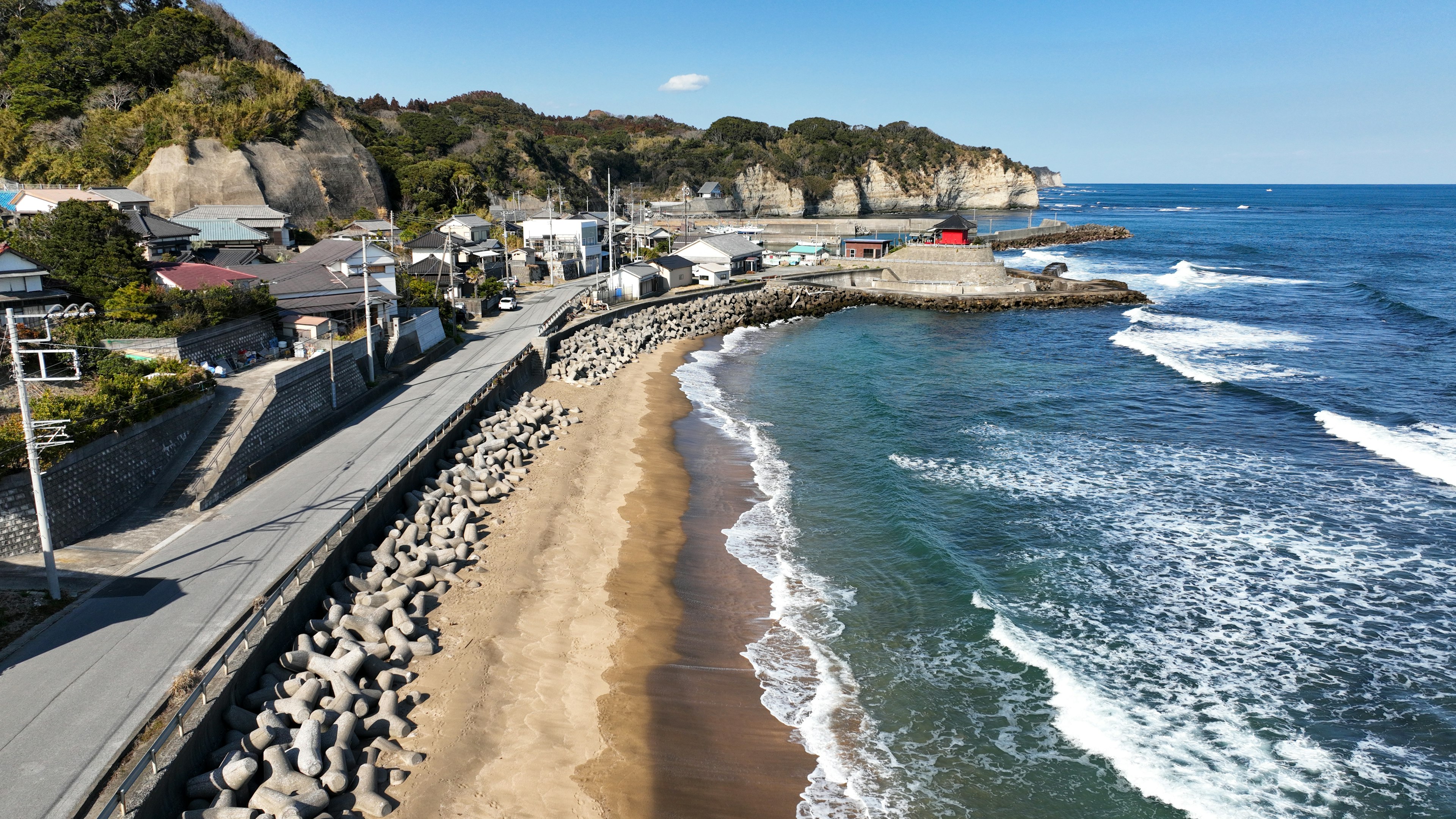 Coastal view with a beach and waves houses and road visible