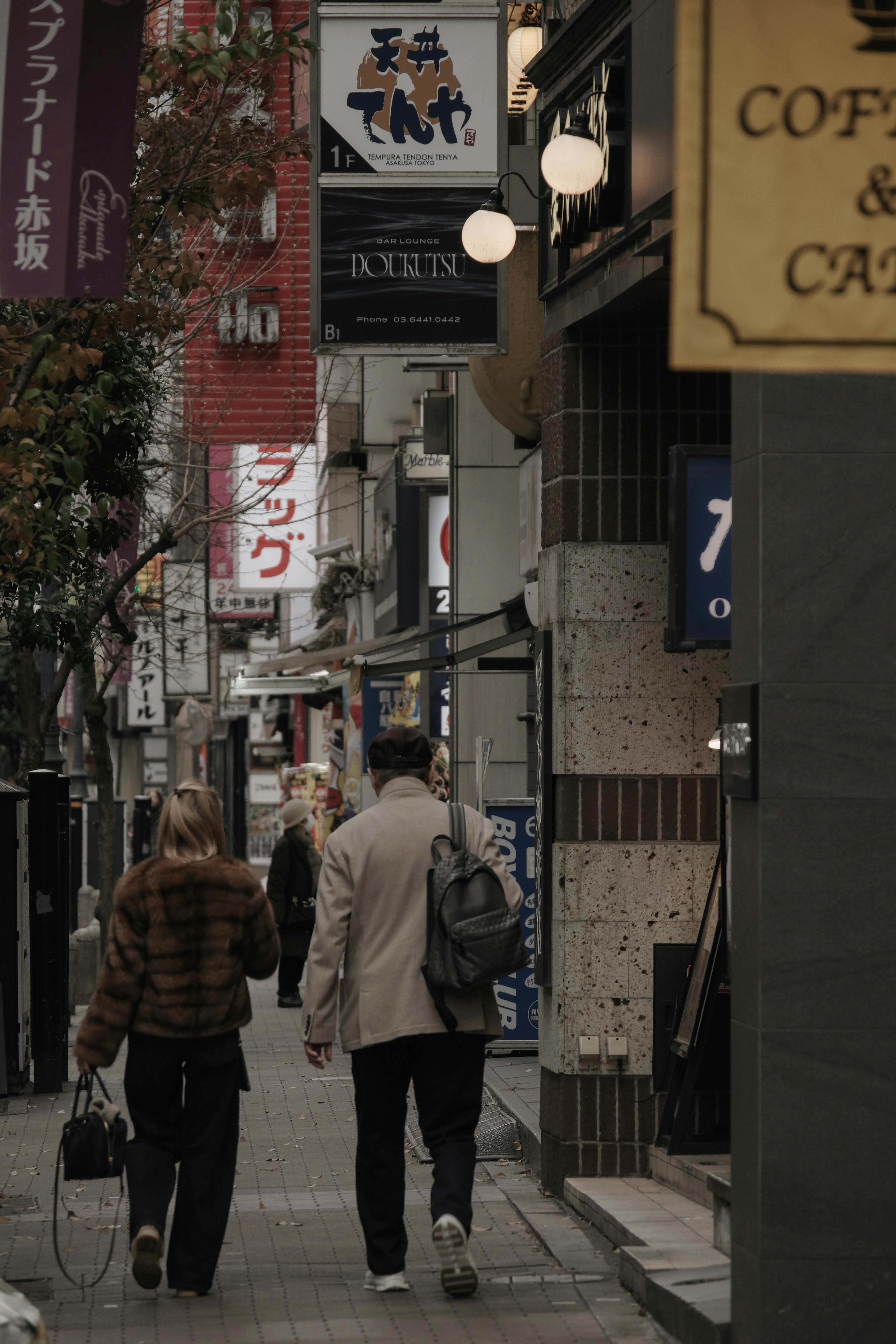 街中を歩く二人の人物と看板が並ぶ風景