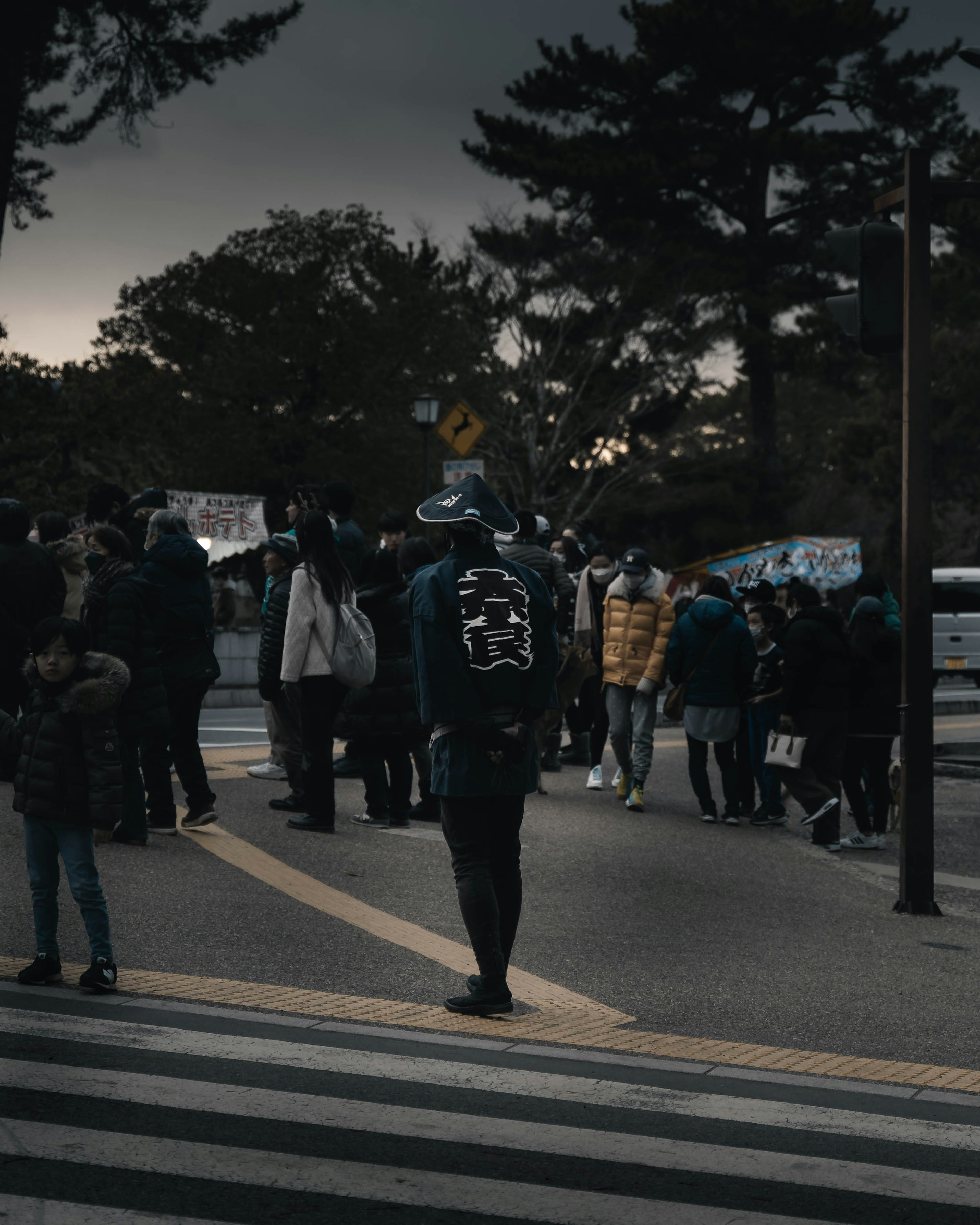 Une scène de personnes traversant une rue avec un individu proéminent sous un ciel sombre