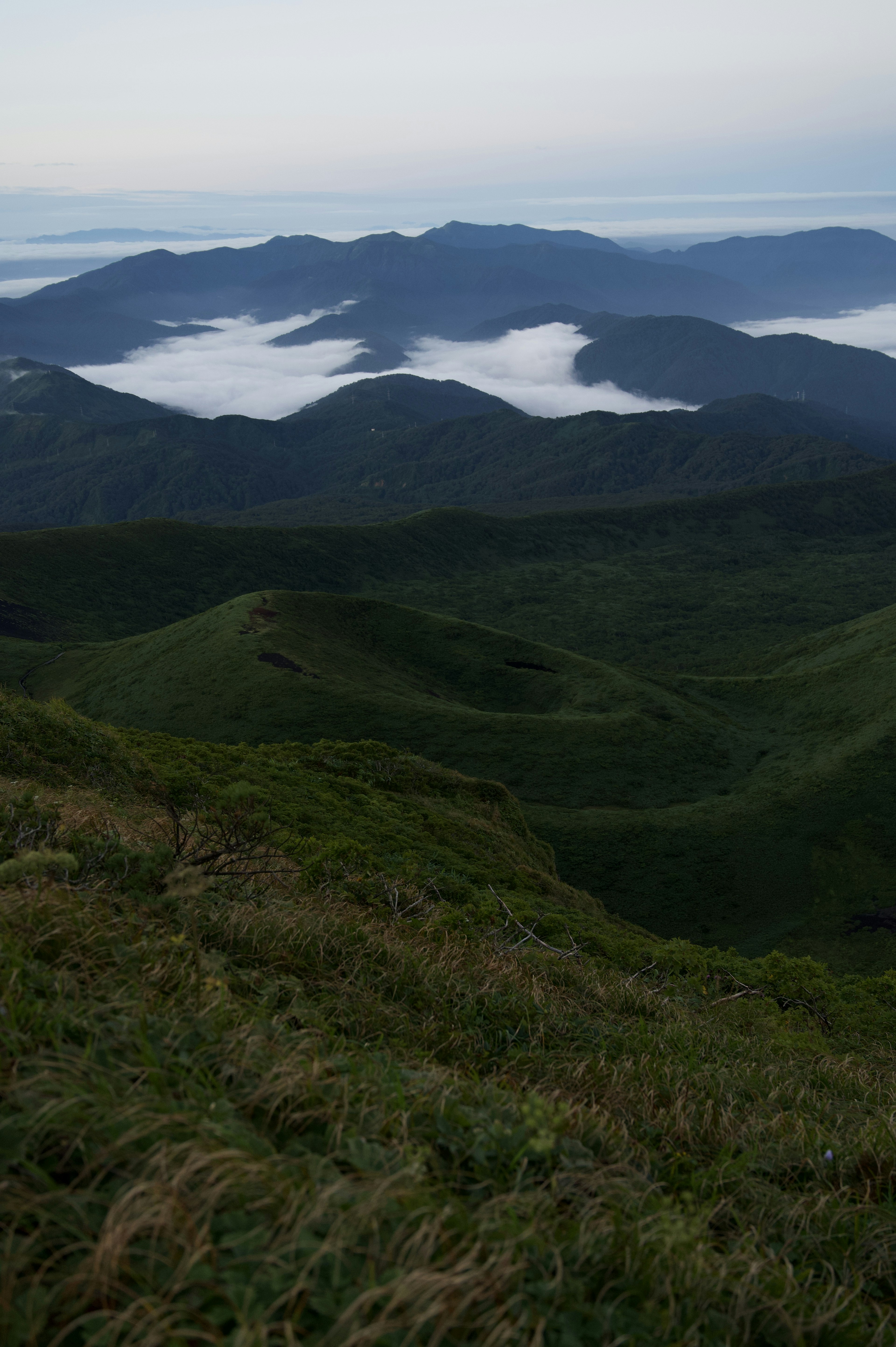 Paisaje montañoso con colinas verdes y un mar de nubes