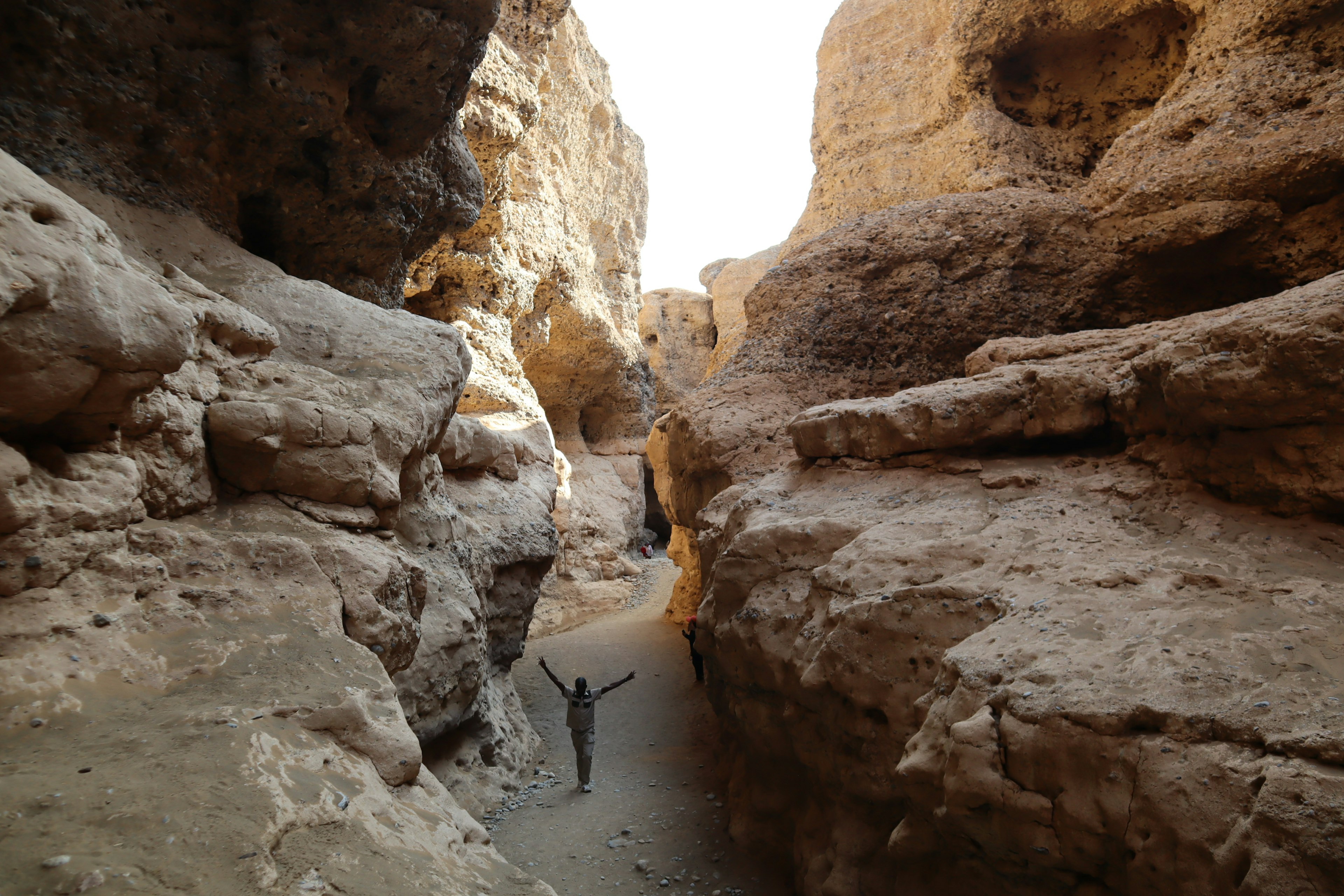 Silhouette di una persona che si erge in un stretto canyon roccioso con scogliere circostanti