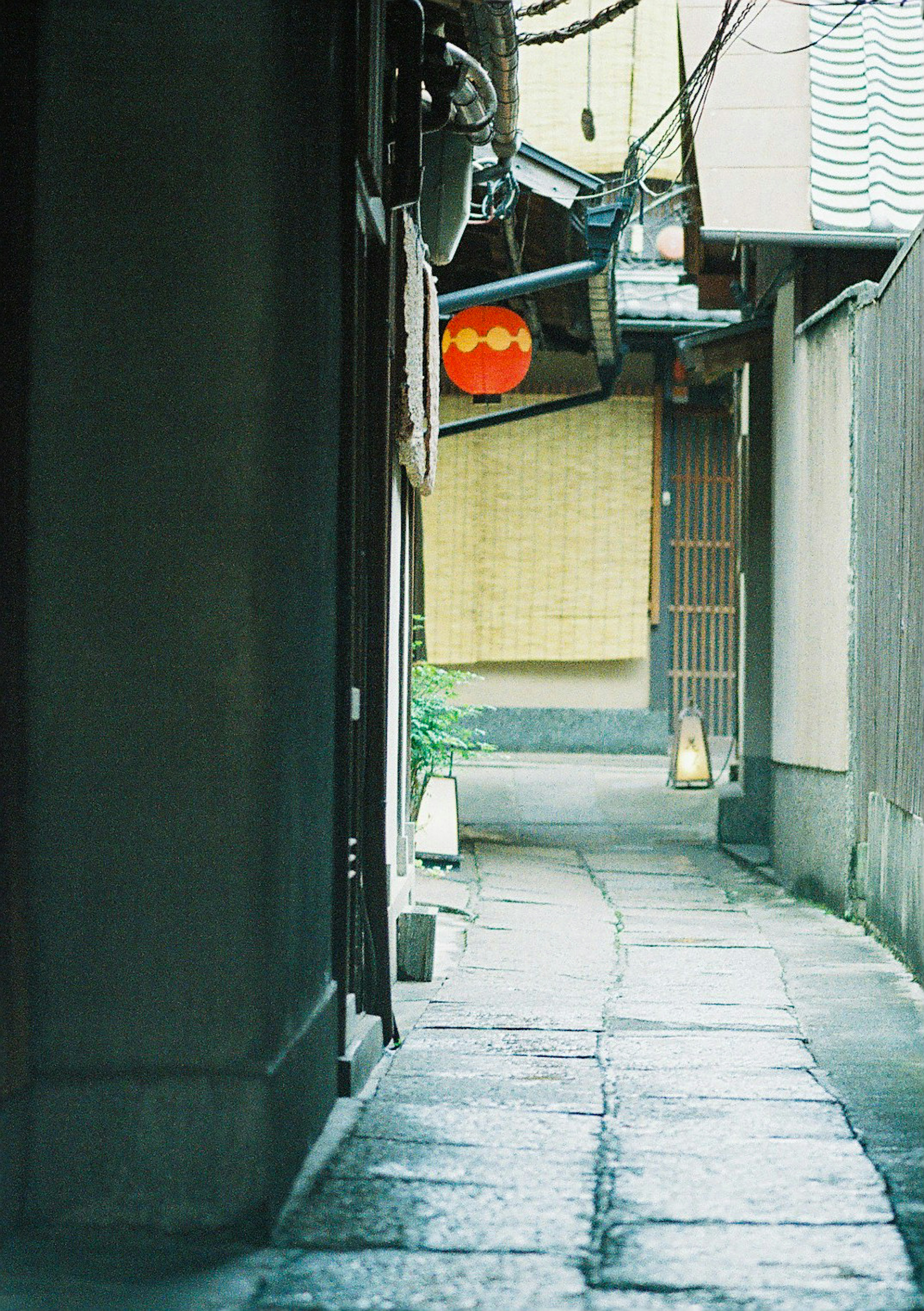 Narrow alley with a red lantern hanging and cobblestone path