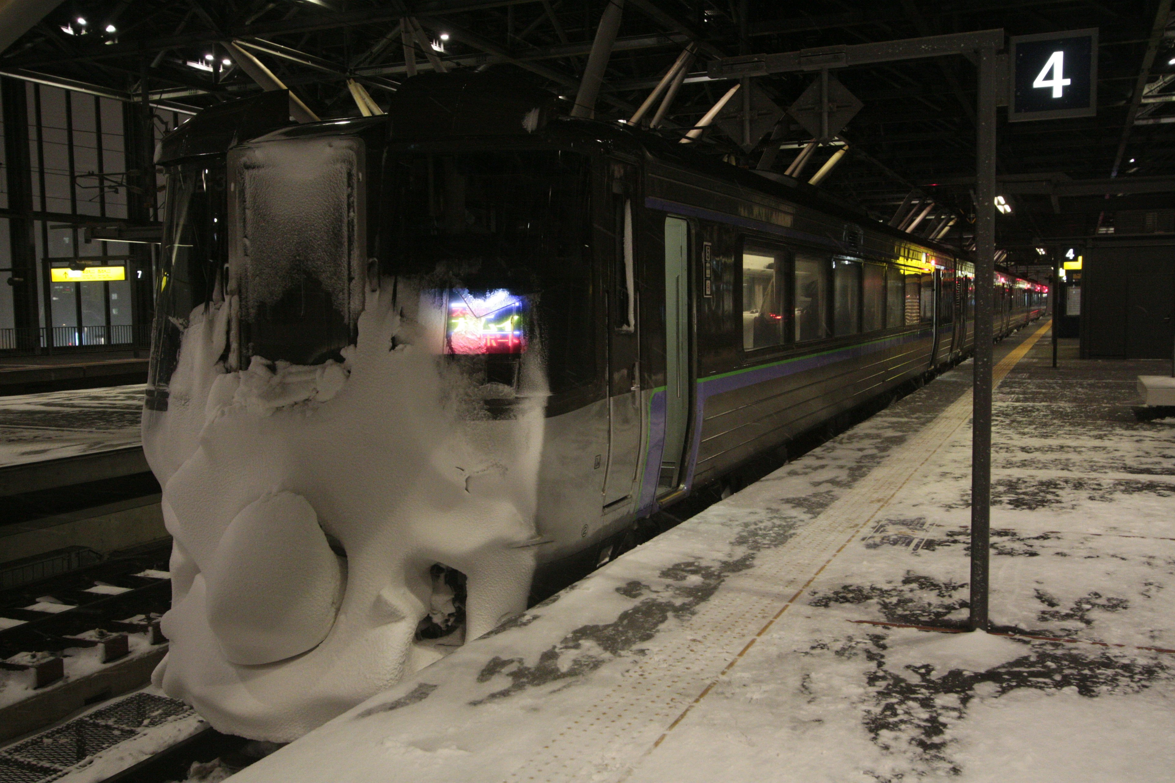 Un train recouvert de neige sur un quai de gare