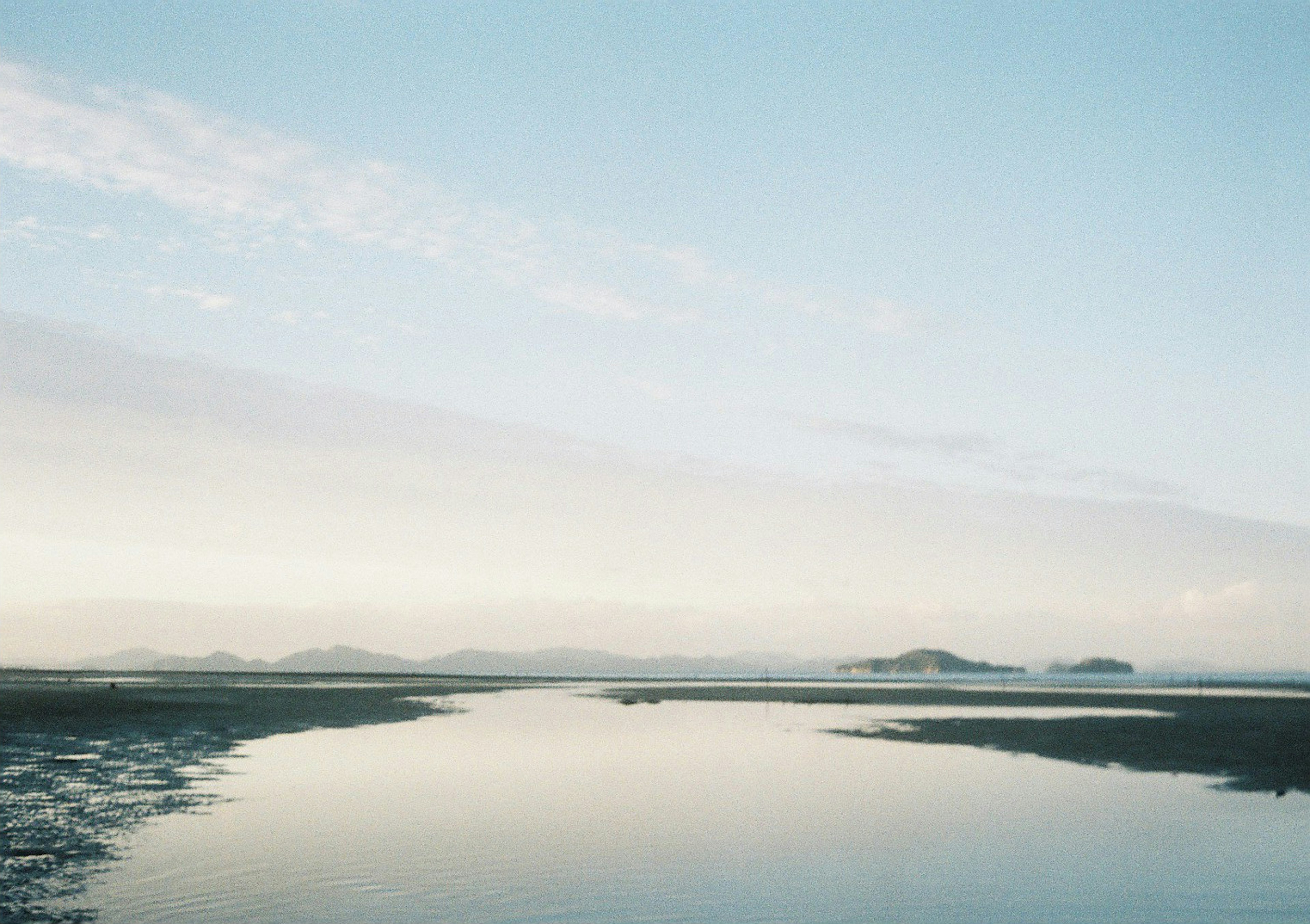 Eine ruhige Landschaft mit blauem Himmel und ruhiger Wasseroberfläche