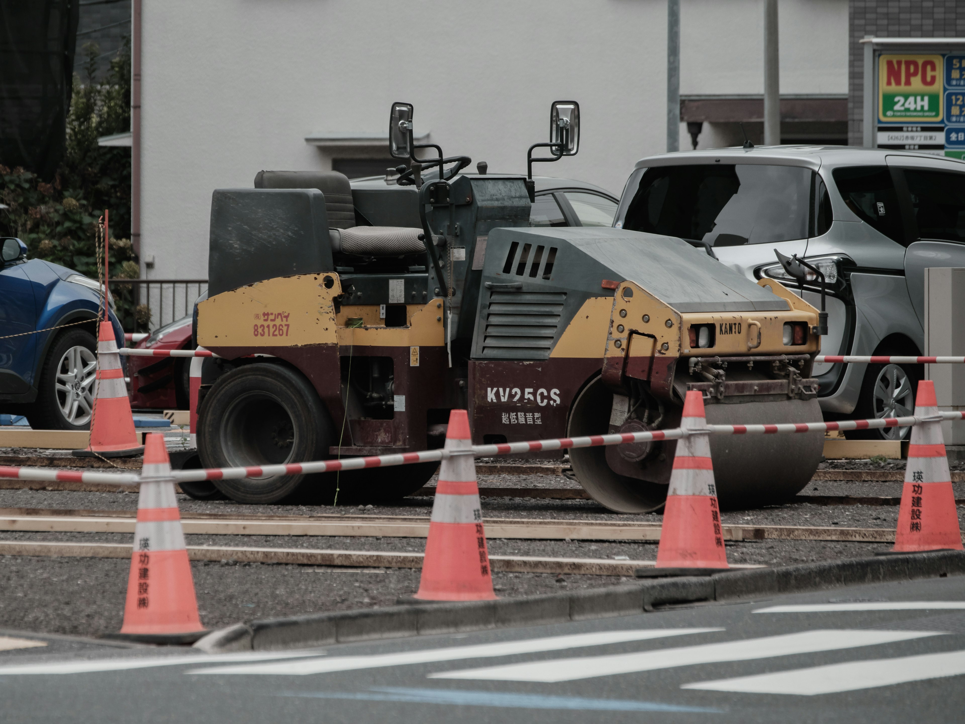 Sitio de construcción con un rodillo y conos naranjas en un área de estacionamiento