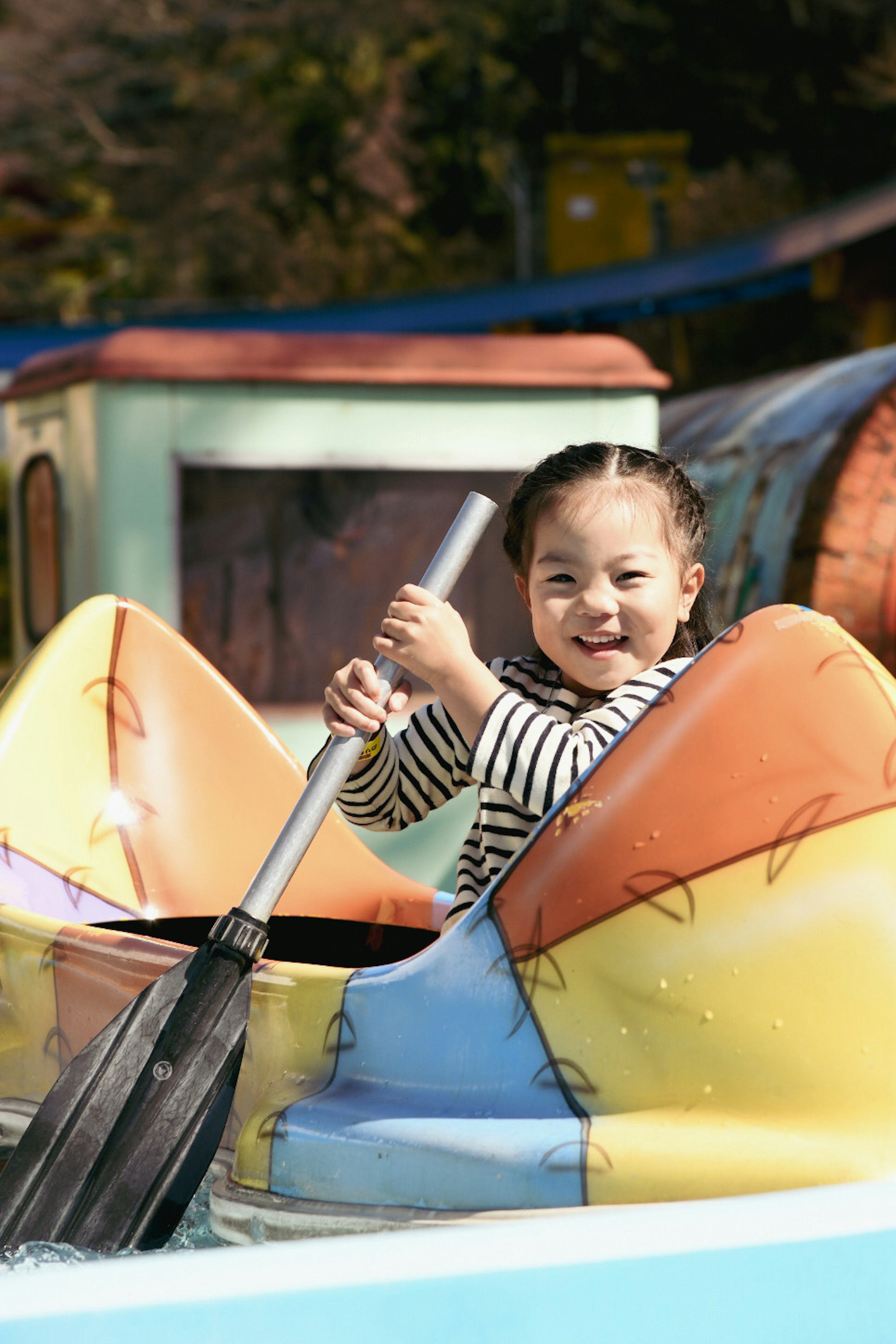 Enfant souriant en pagayant dans un bateau coloré