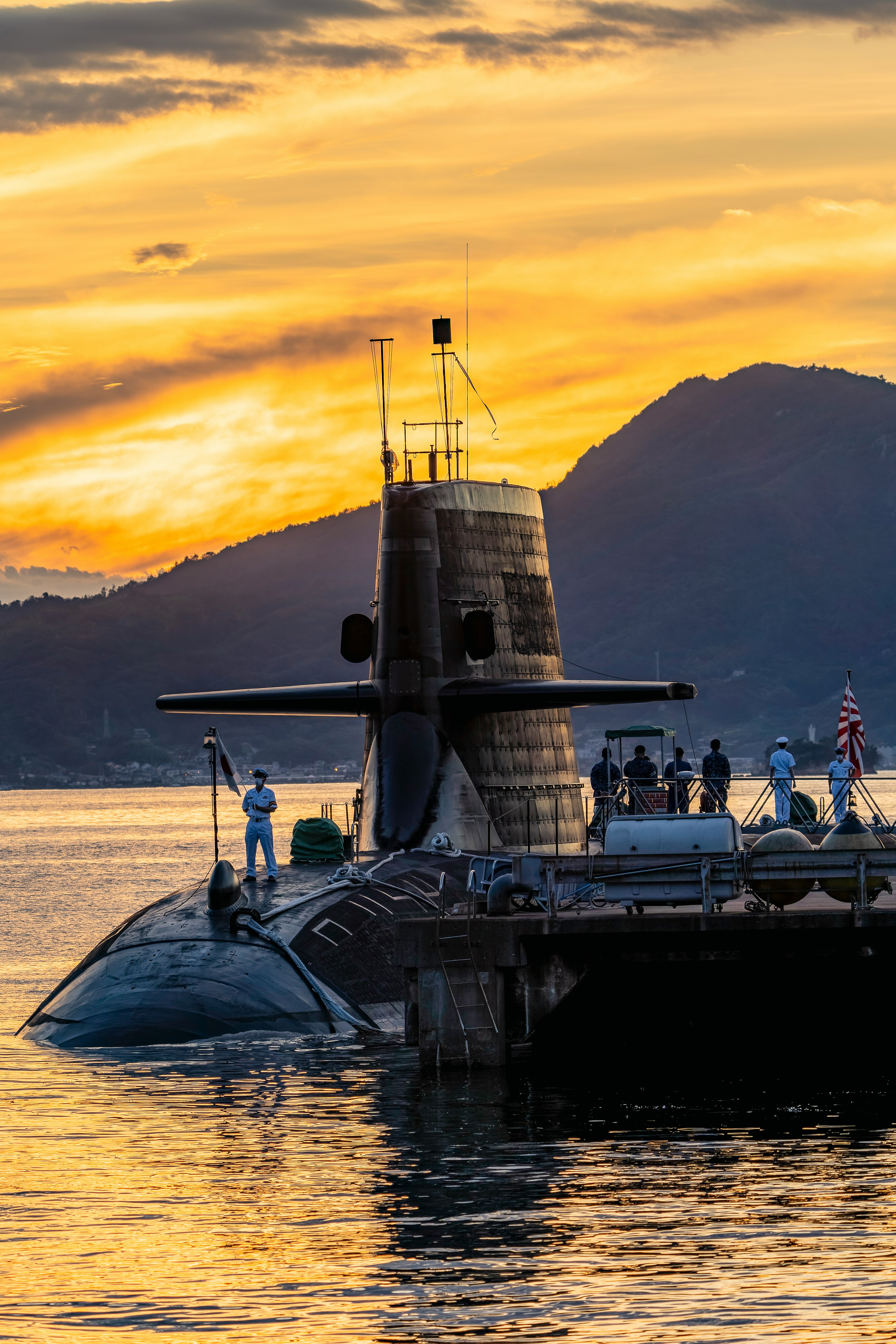 Sous-marin émergeant au coucher de soleil avec des gens autour