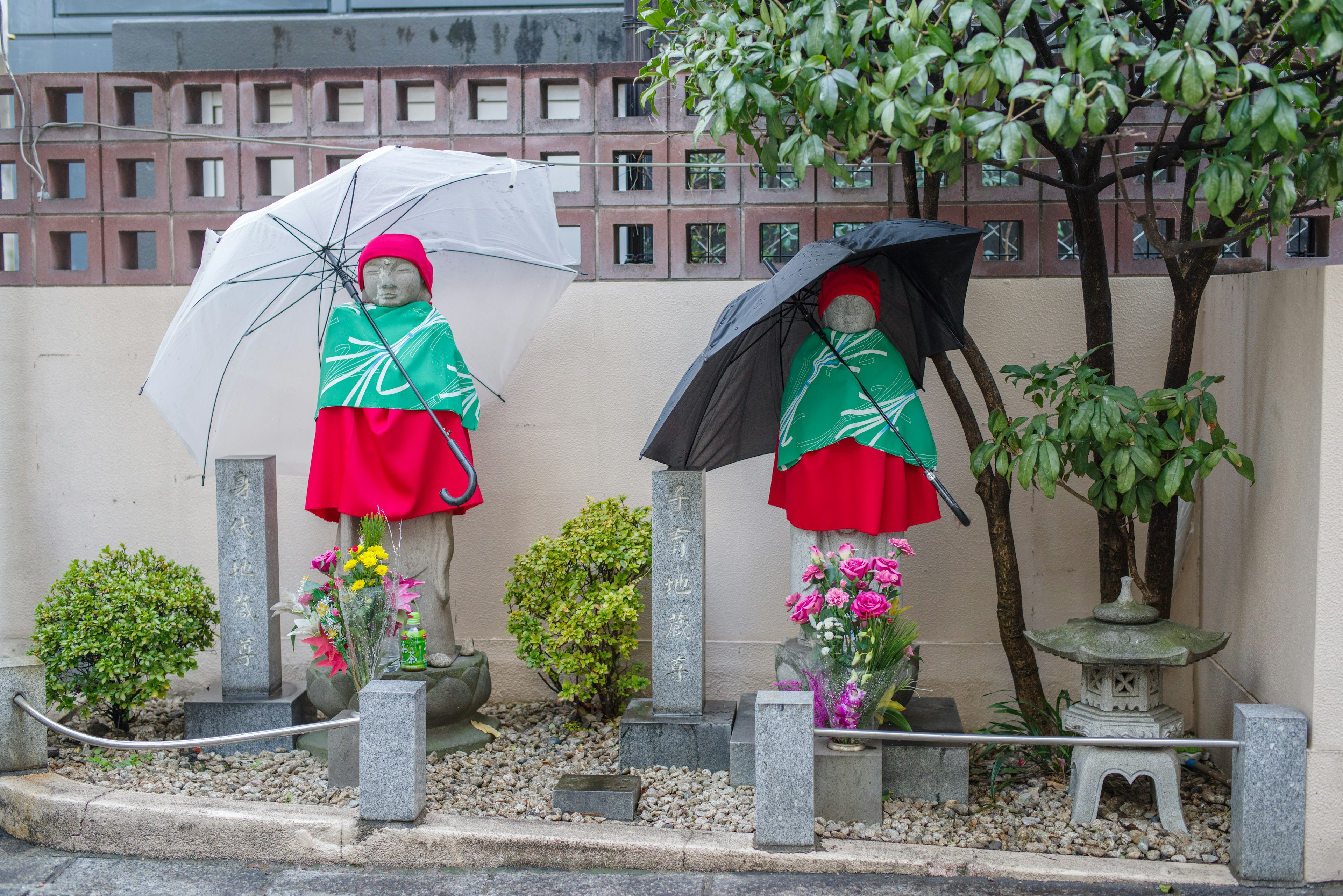 Deux figures en vêtements rouges tenant des parapluies entourées de plantes vertes