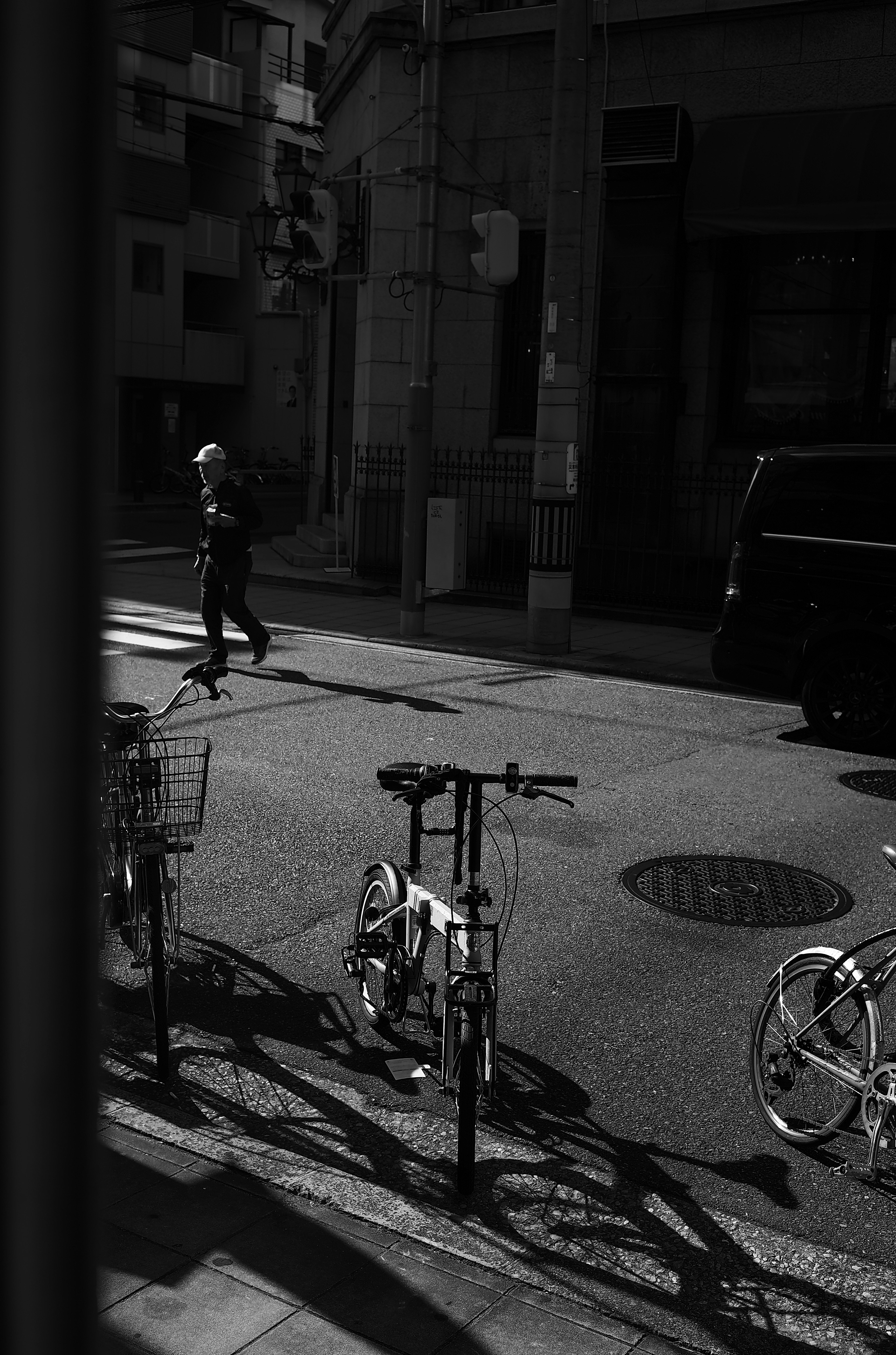 Black and white street scene with bicycles parked and a pedestrian walking