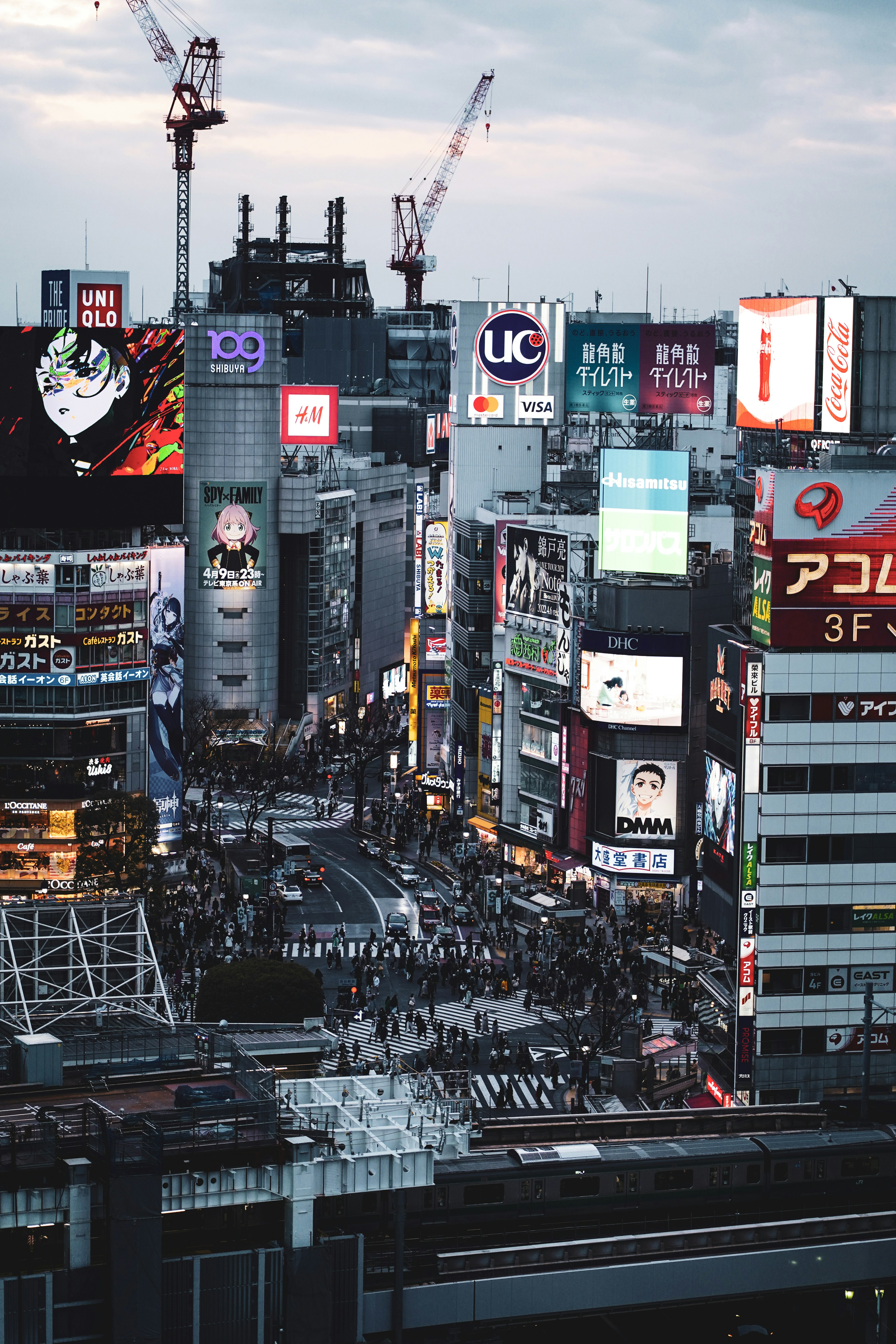 A bustling urban scene in Shibuya with crowds and neon signs at dusk