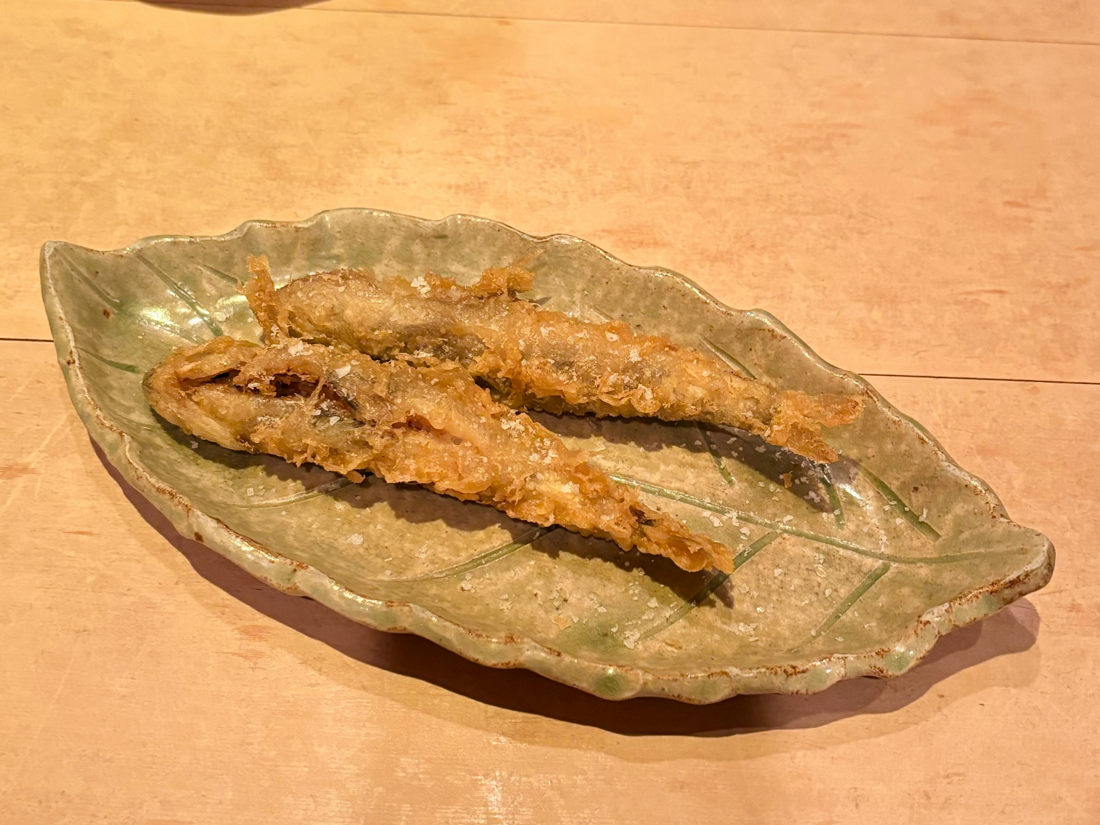 Piatto di pesce fritto servito su un piatto a forma di foglia