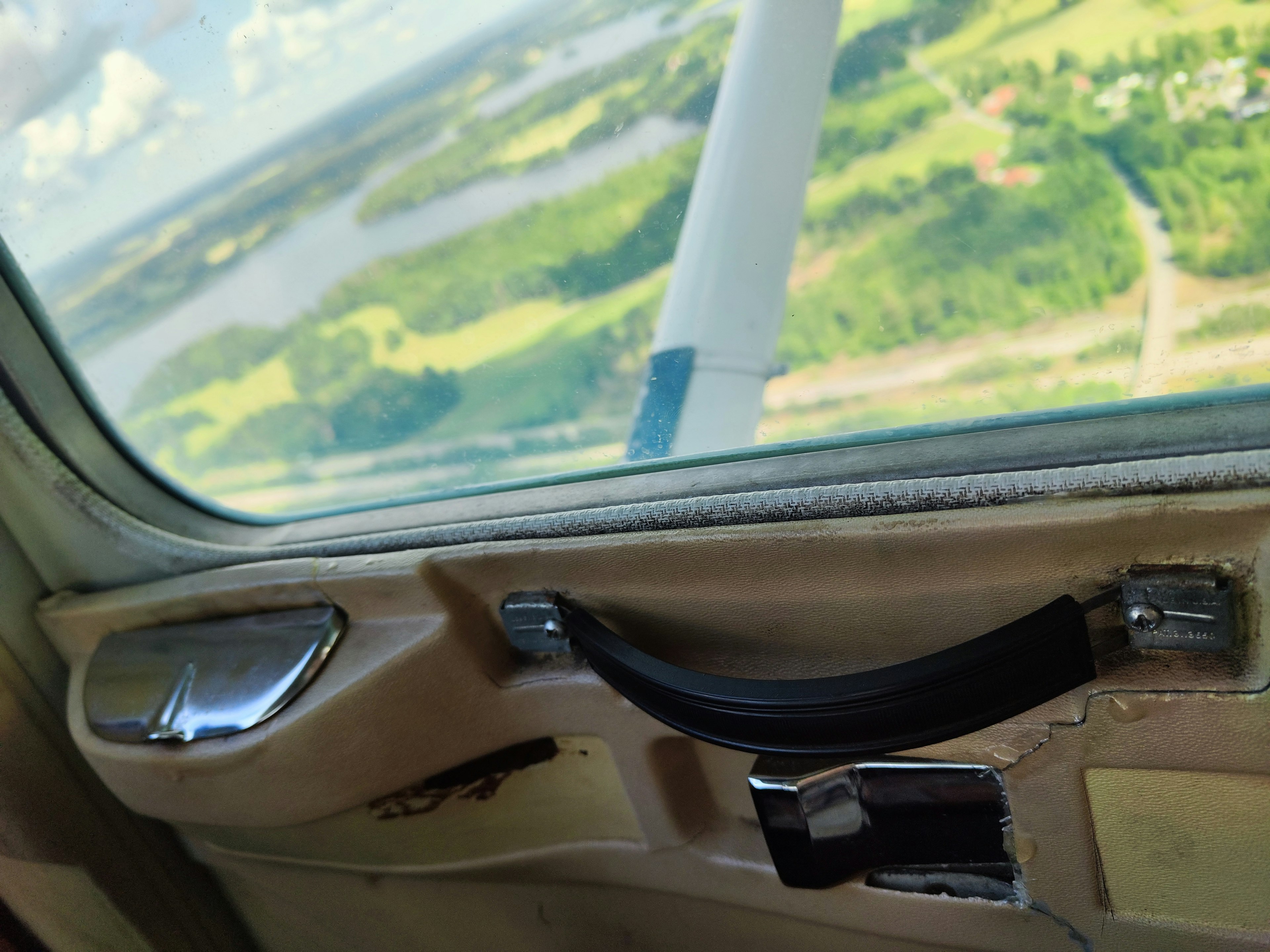 Vue depuis une fenêtre d'avion montrant le paysage et une partie du panneau de contrôle