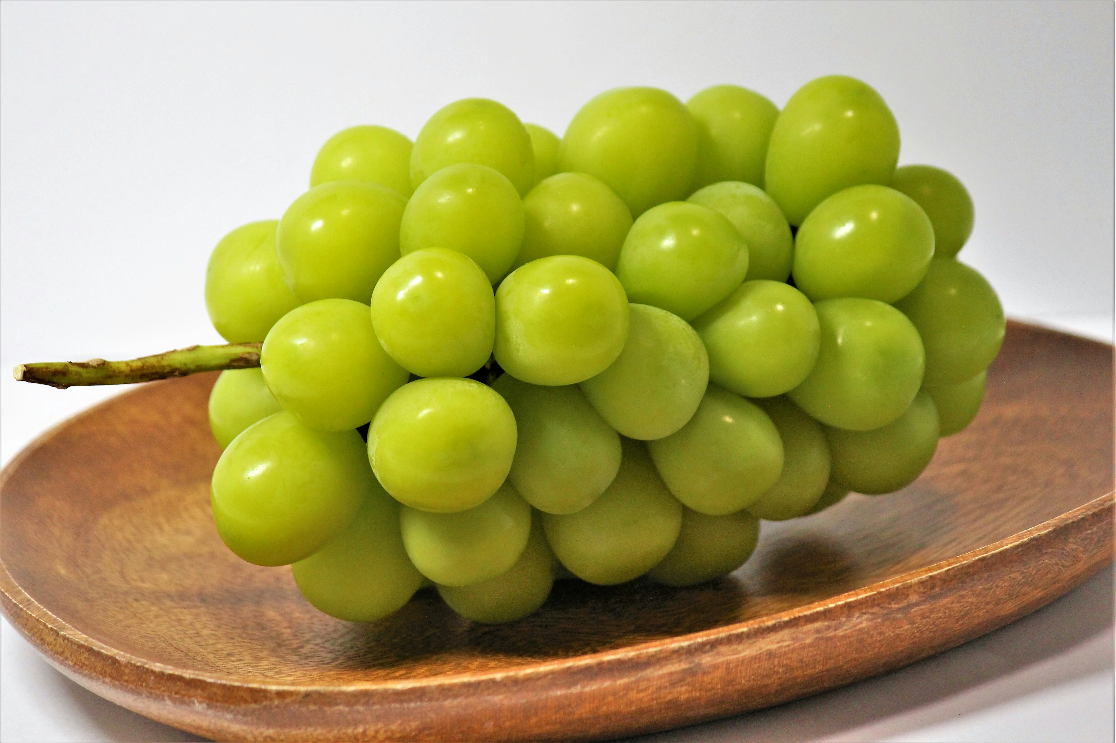 Un racimo de uvas verdes sobre un plato de madera