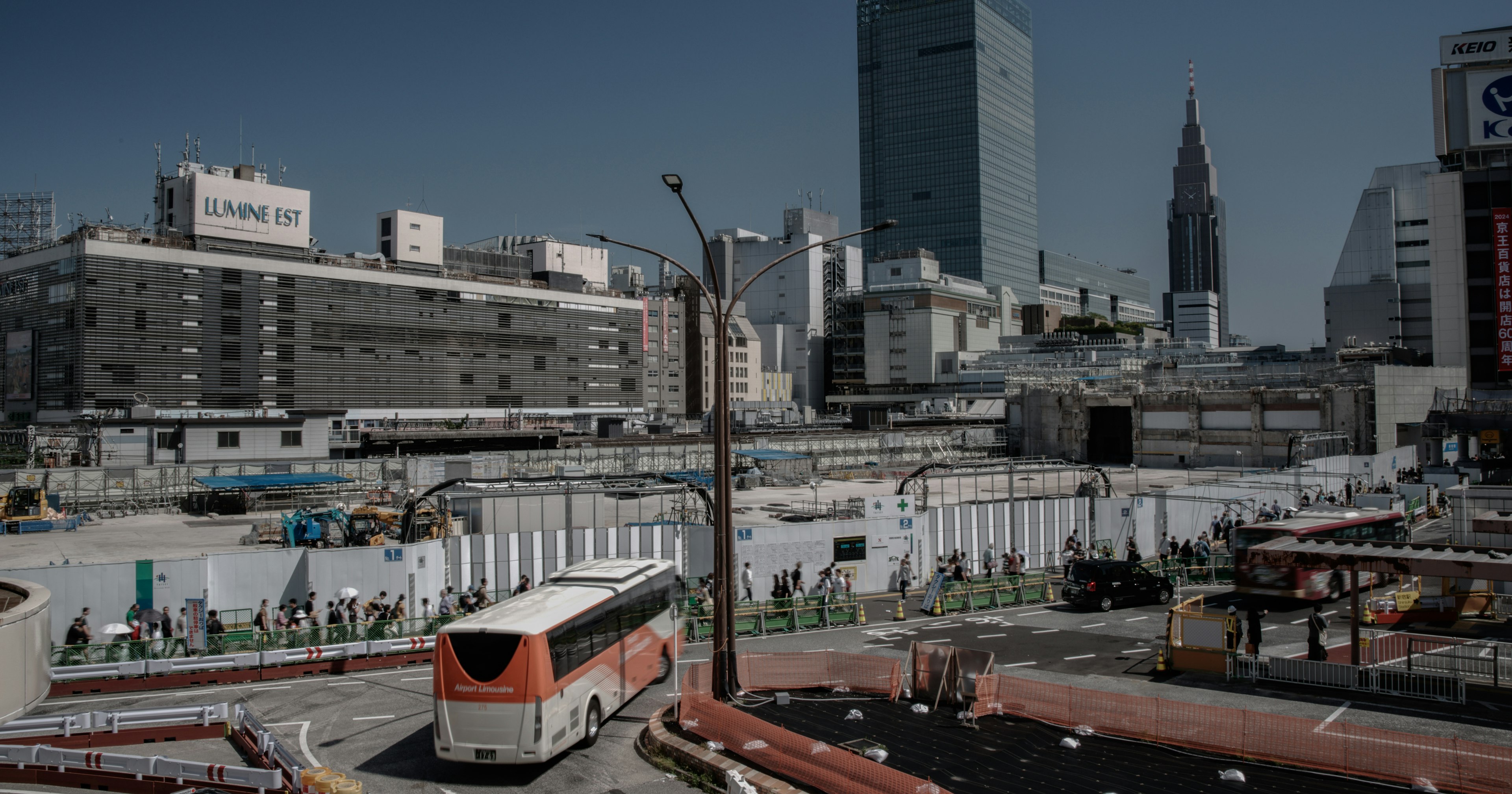 Site de construction urbain avec un bus visible bâtiments et grues en arrière-plan