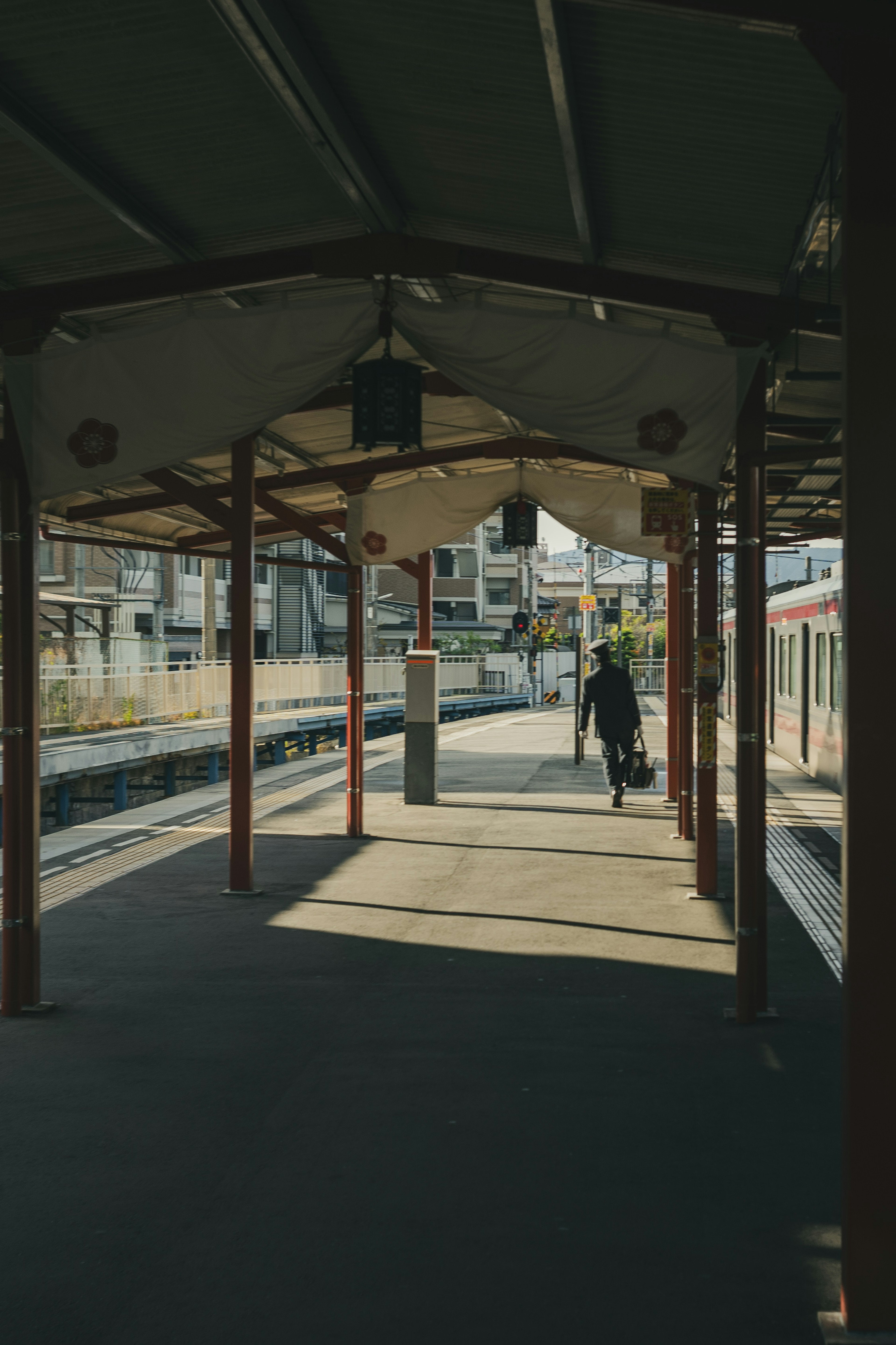 Una persona che cammina su una piattaforma ferroviaria con ombre e prospettive suggestive