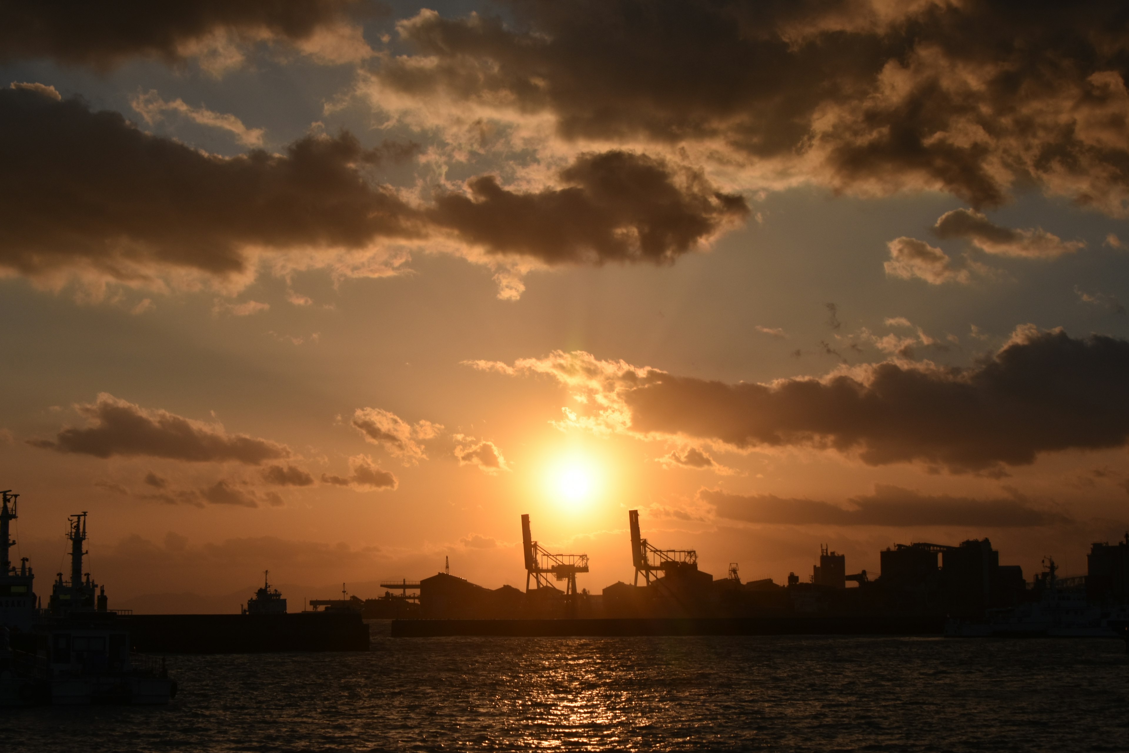 Sonnenuntergang über dem Hafen mit silhouettierten Kränen