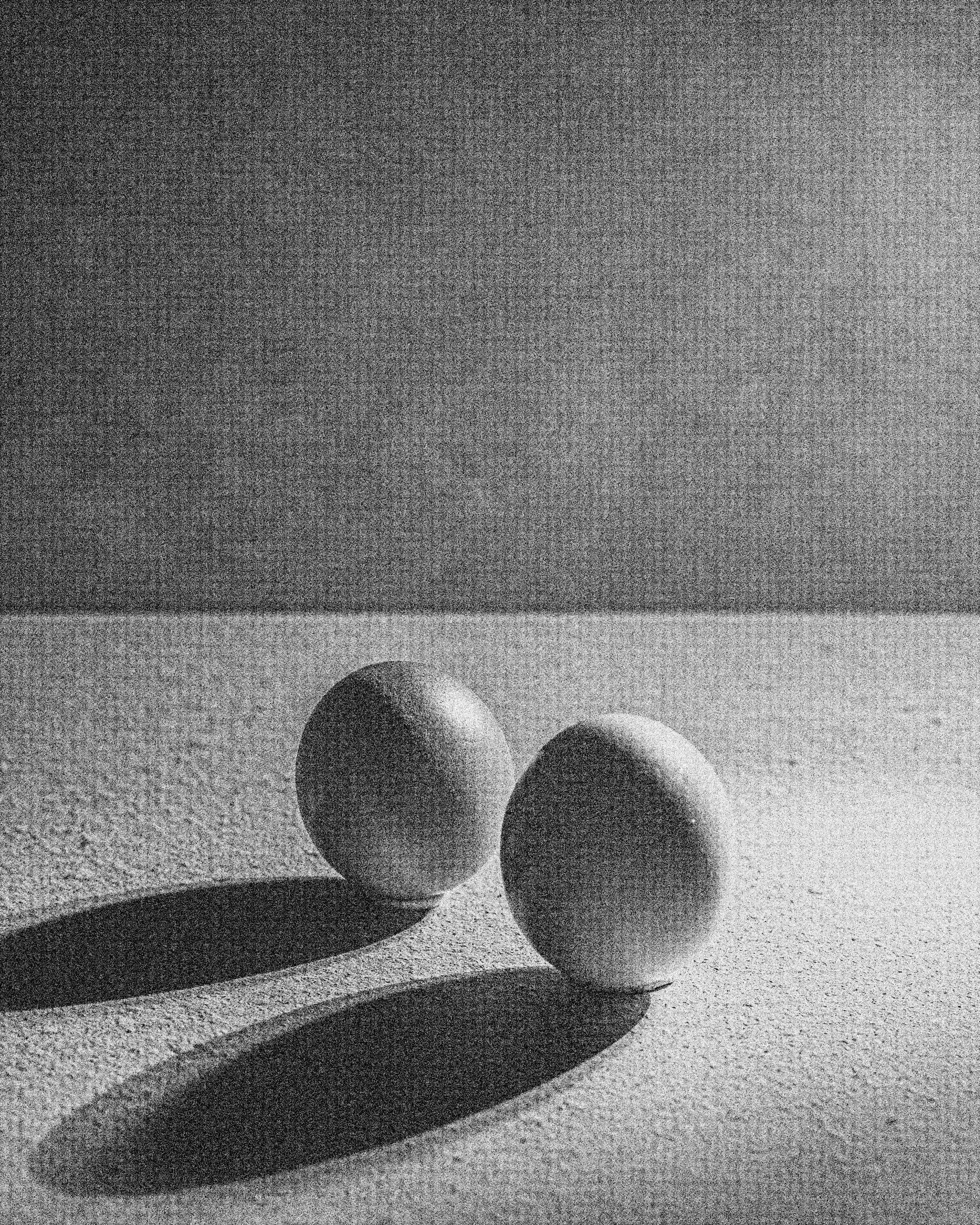 Two white spheres positioned closely on a textured surface in monochrome