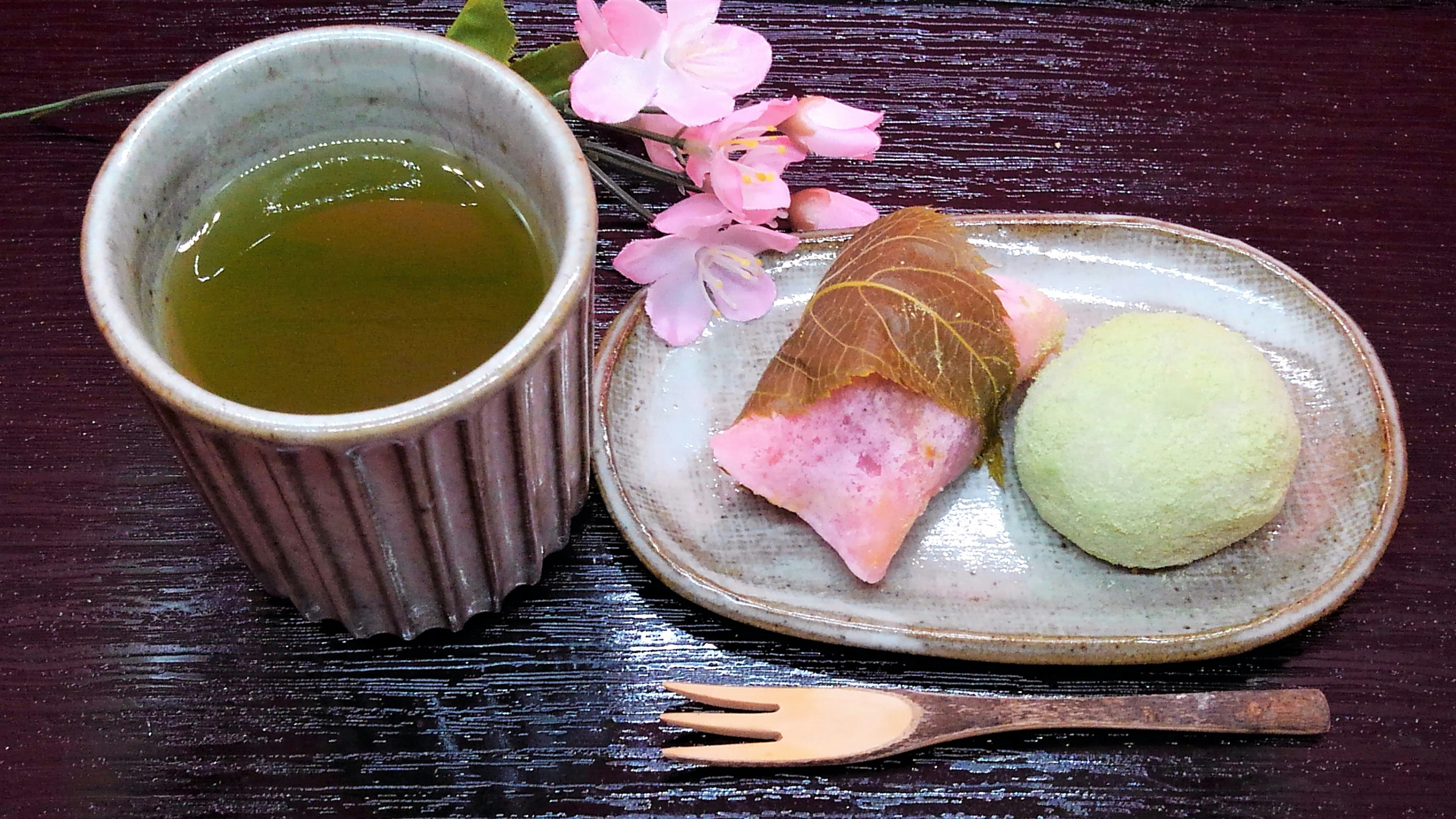 Ein Teller mit Matcha-Tee und traditionellen japanischen Süßigkeiten mit Sakura- und Grüntee-Geschmack