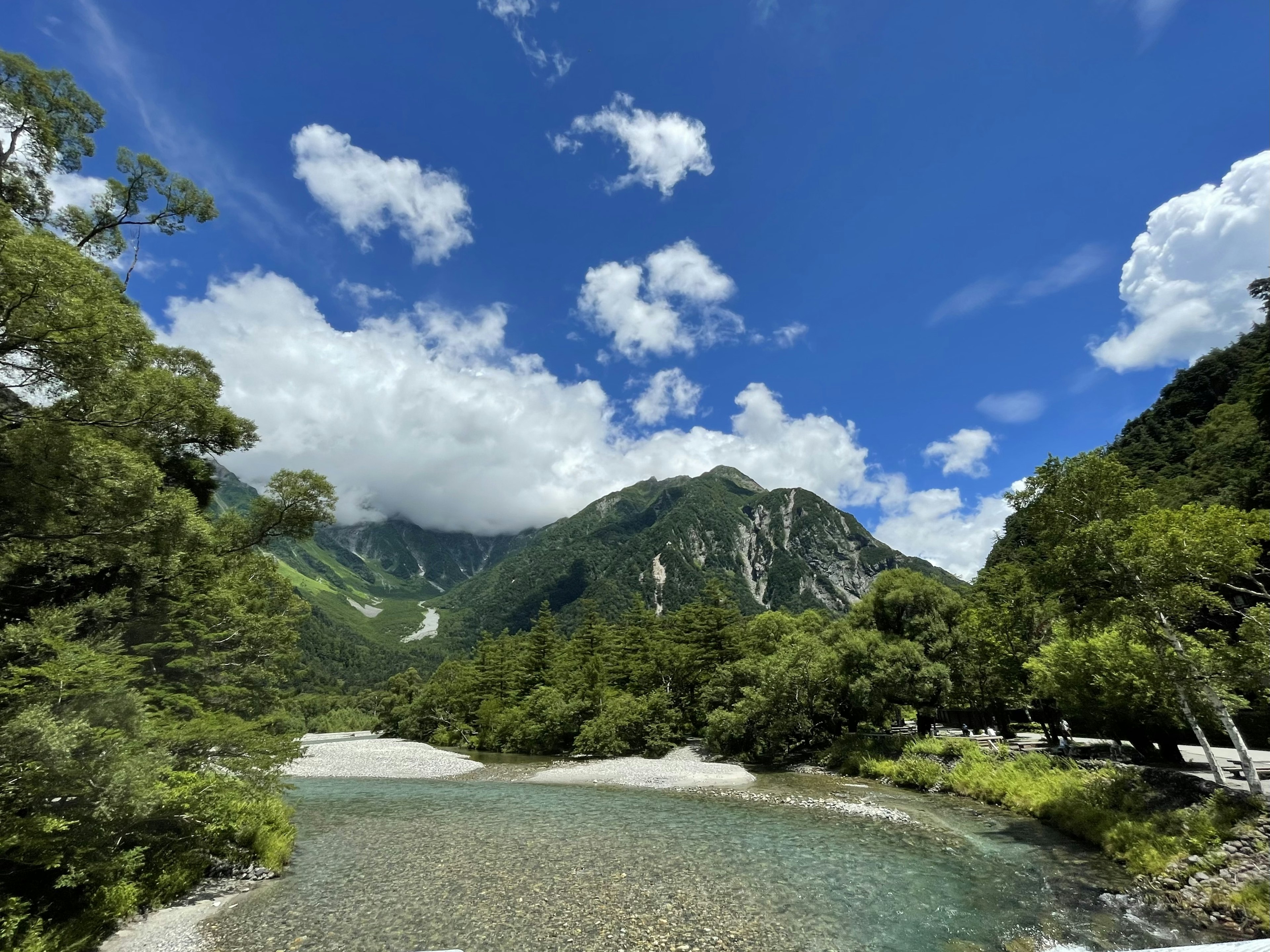 青空と雲が広がる山と川の風景 緑豊かな木々に囲まれた穏やかな水面