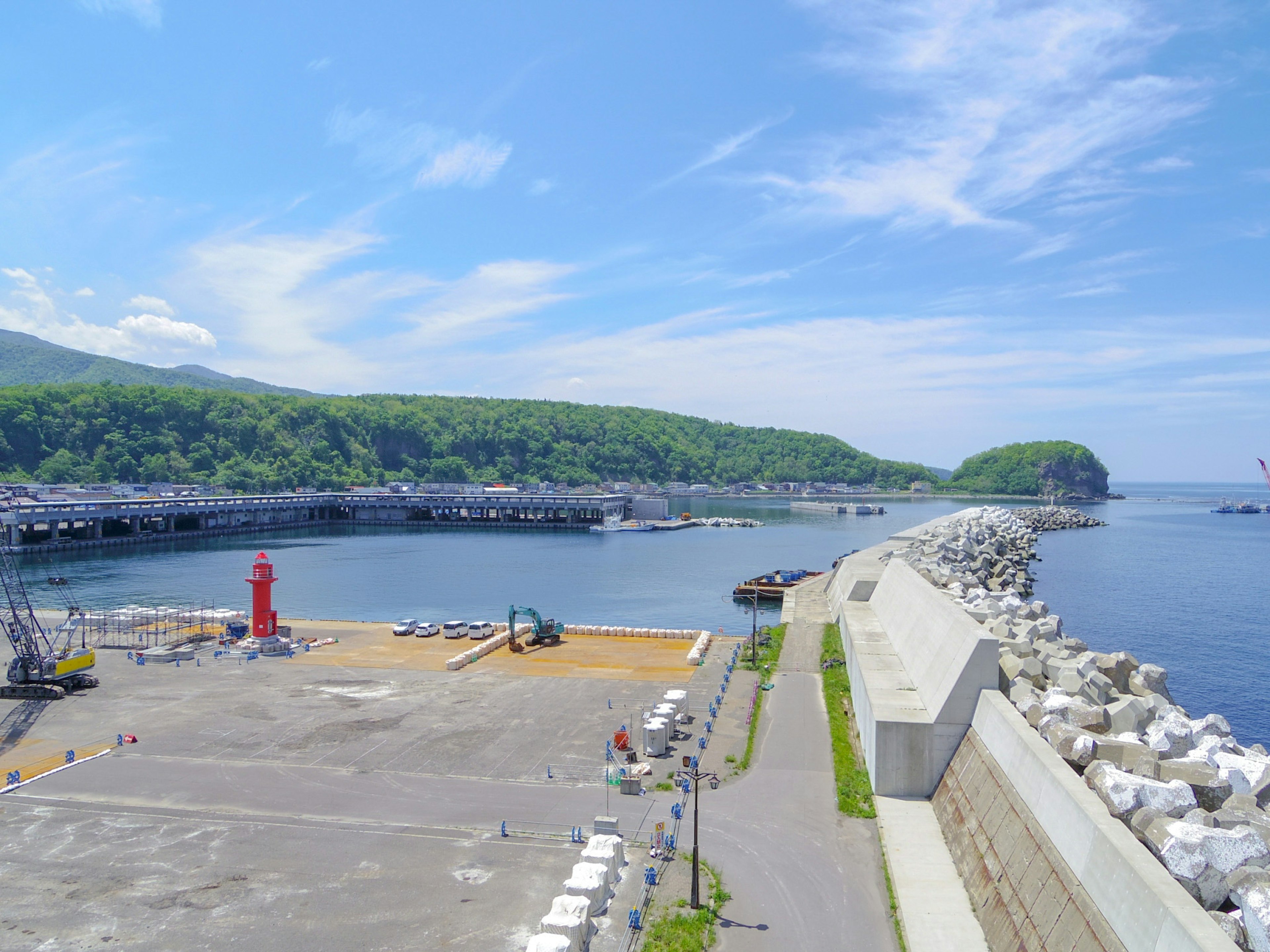 Harbor view featuring blue sky green mountains and a red lighthouse