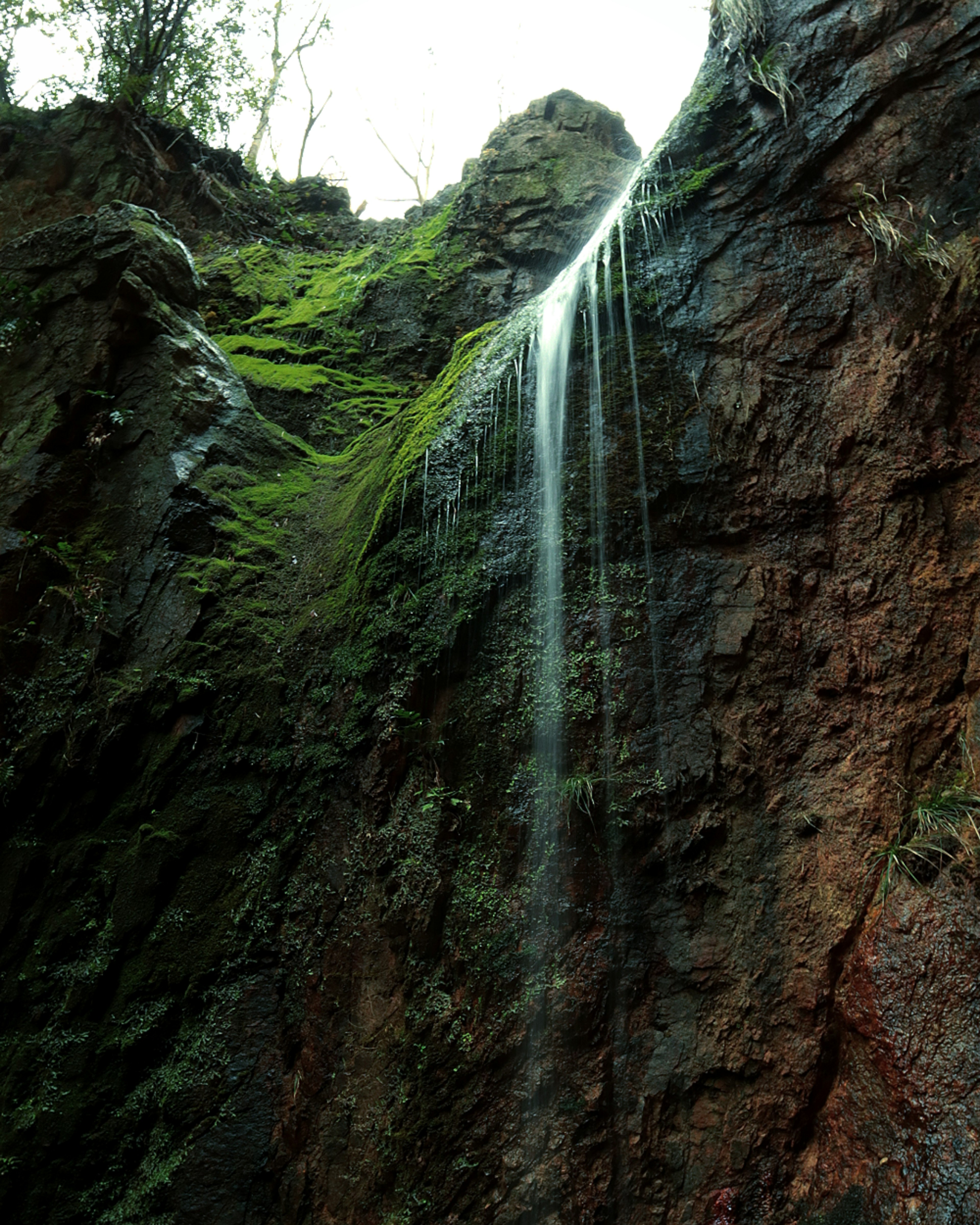 Schöne Aussicht auf einen Wasserfall, der über eine moosbedeckte Felswand fließt