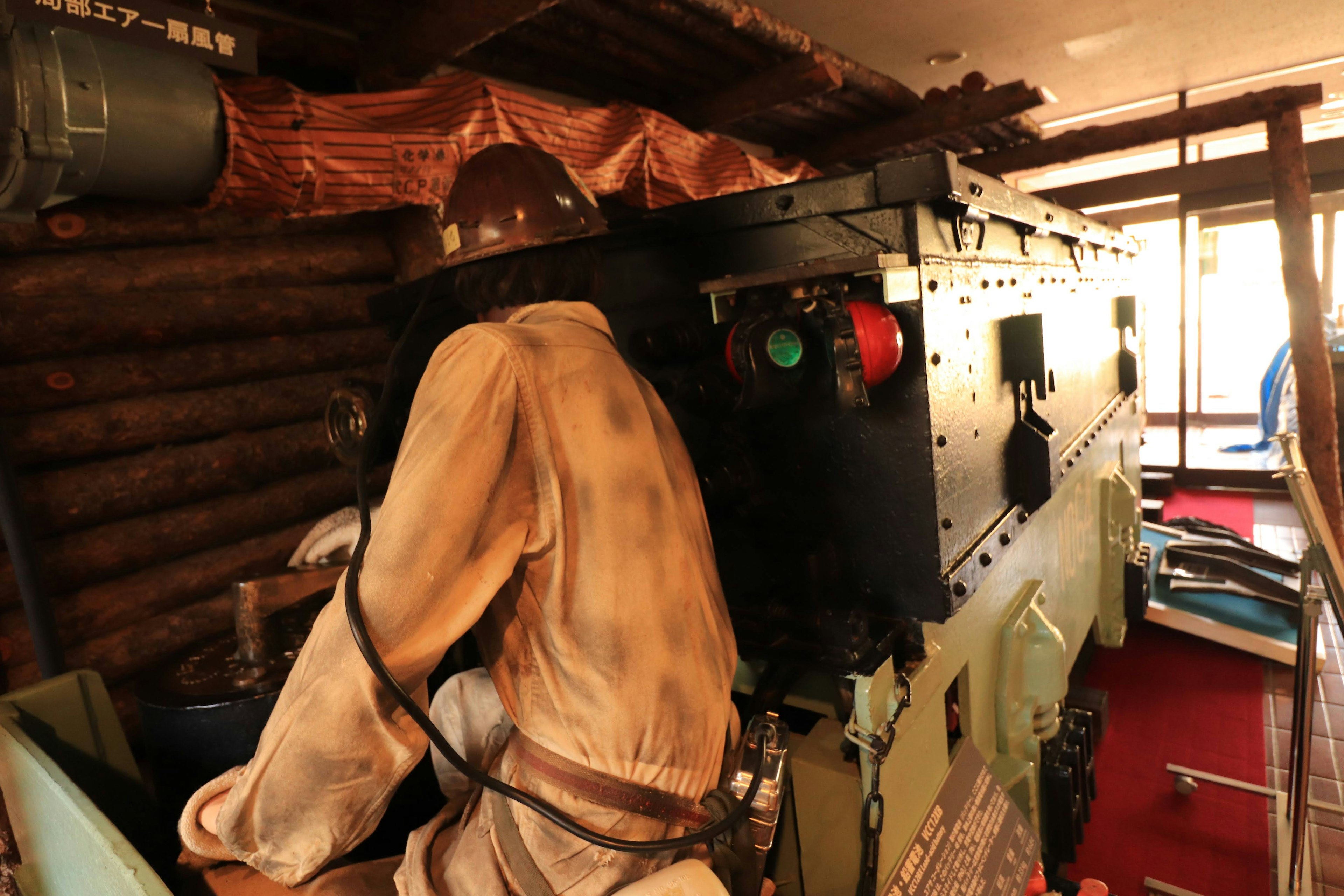 A figure operating machinery inside a cabin with various controls