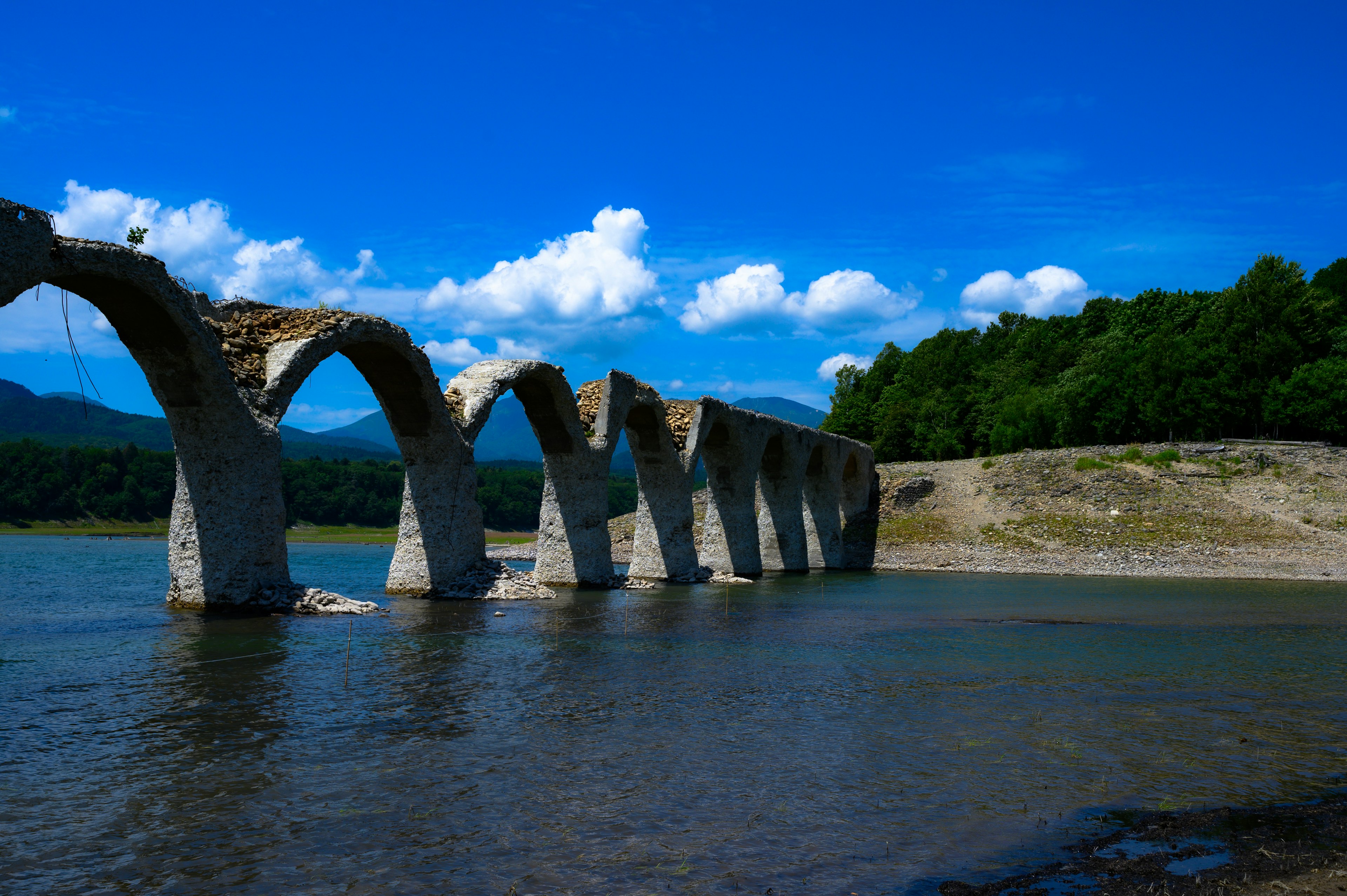 Ruinas de un puente arqueado bajo un hermoso cielo azul