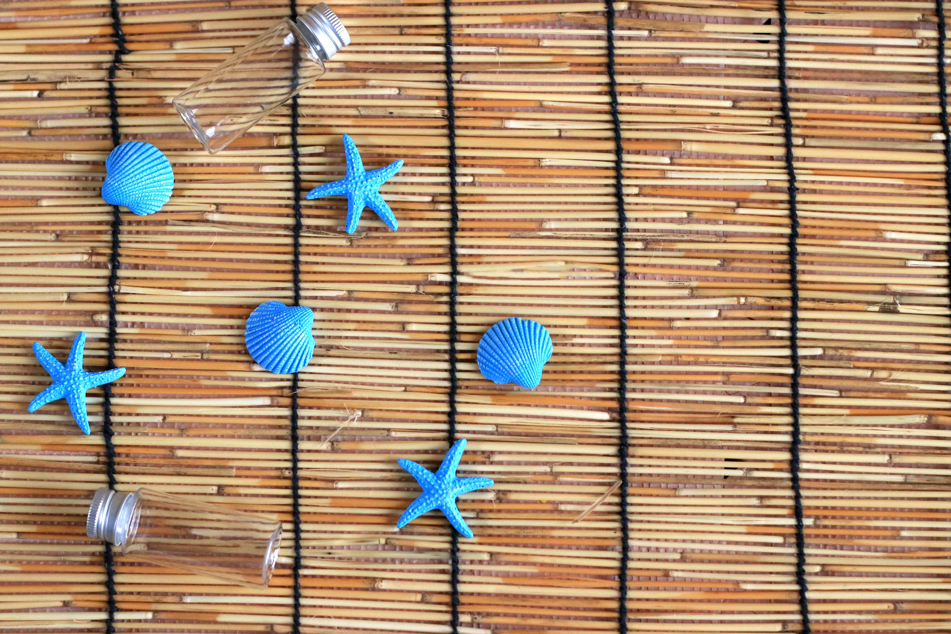 Décorations en forme d'étoile bleue et coquillages disposés sur une table en bambou