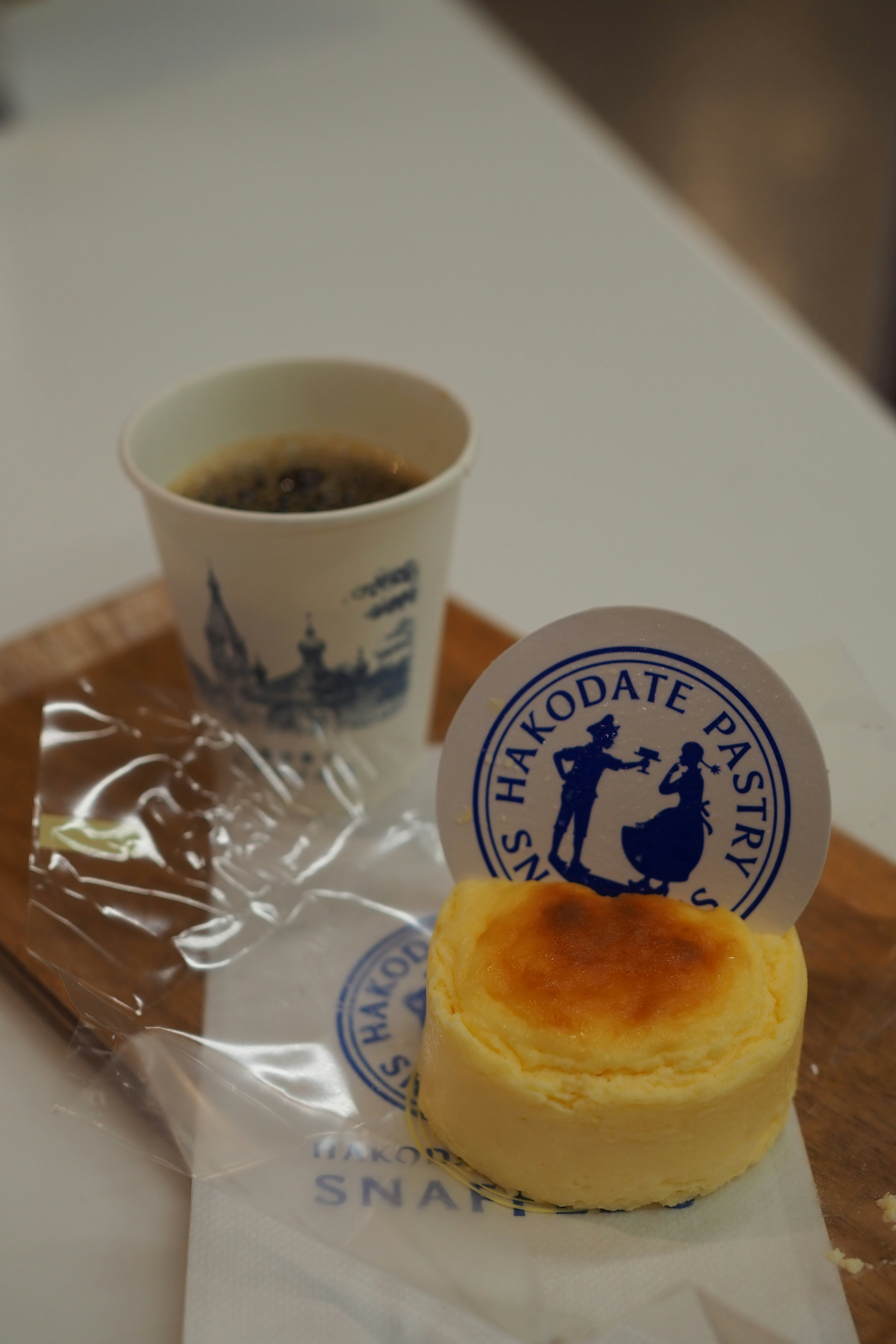 Cup of coffee with a soufflé cheesecake on a wooden board featuring a blue design