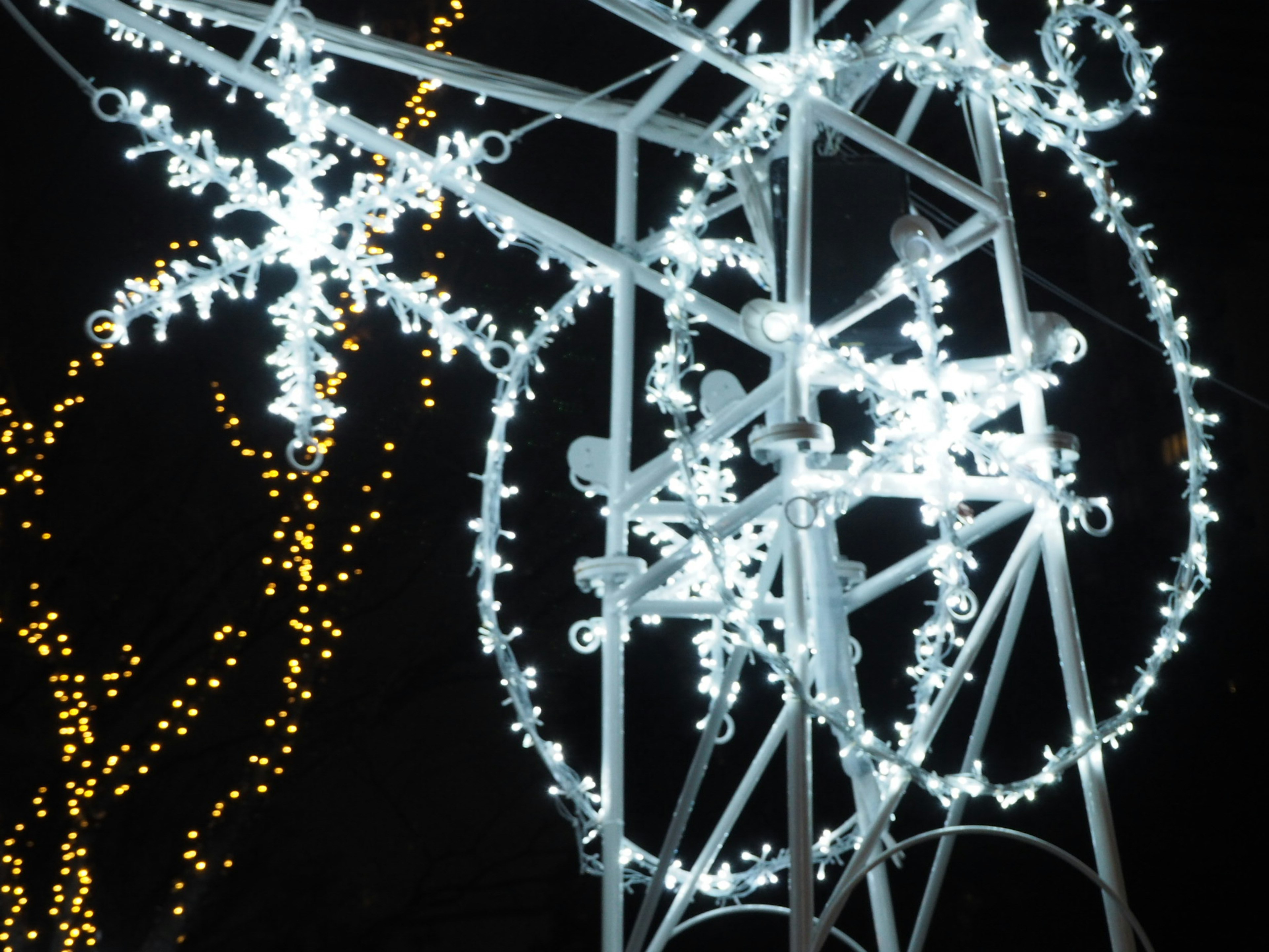 White light snowflakes and circular decorations shining against a night sky