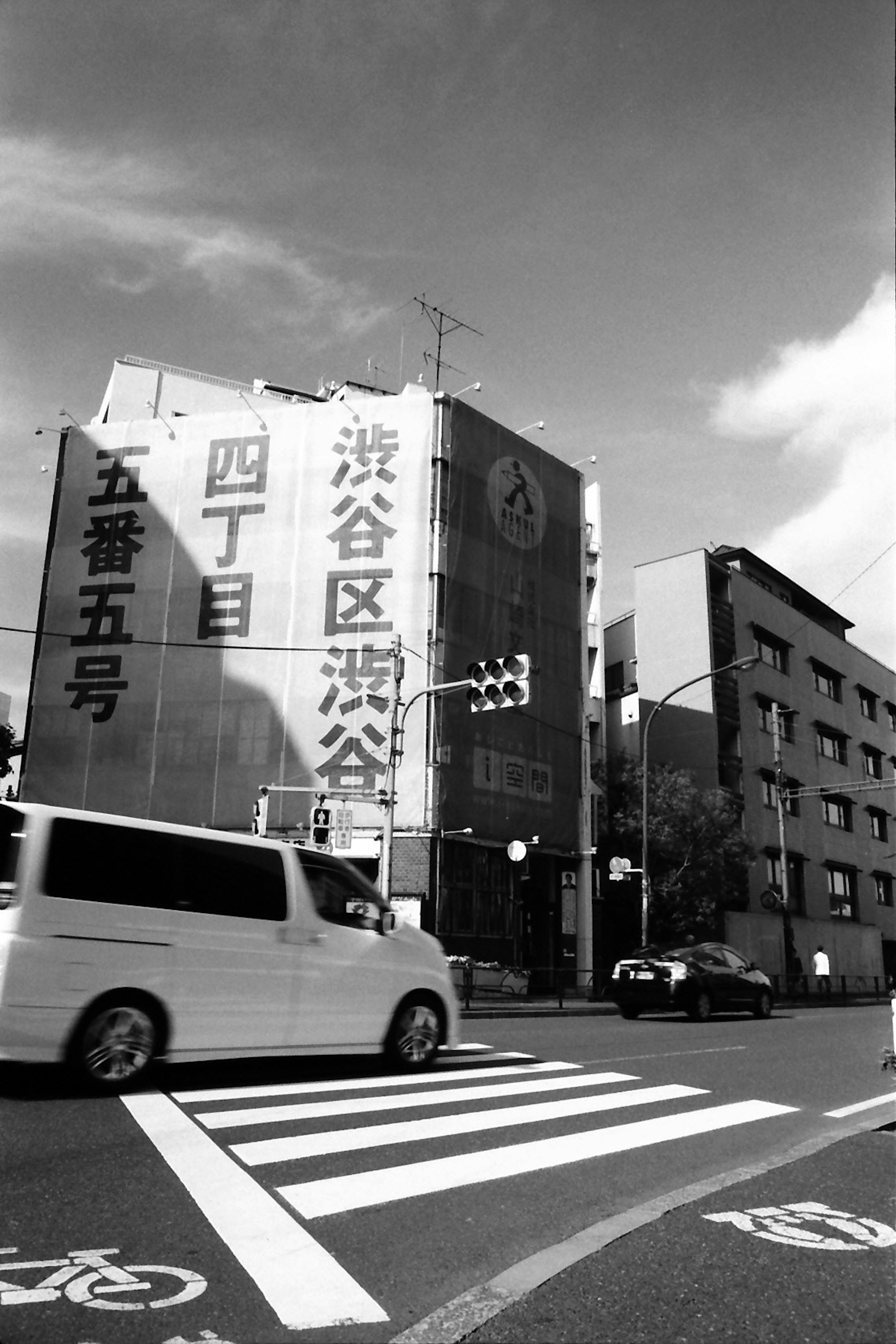 Image en noir et blanc d'un bâtiment à une intersection de Shibuya avec un feu de circulation