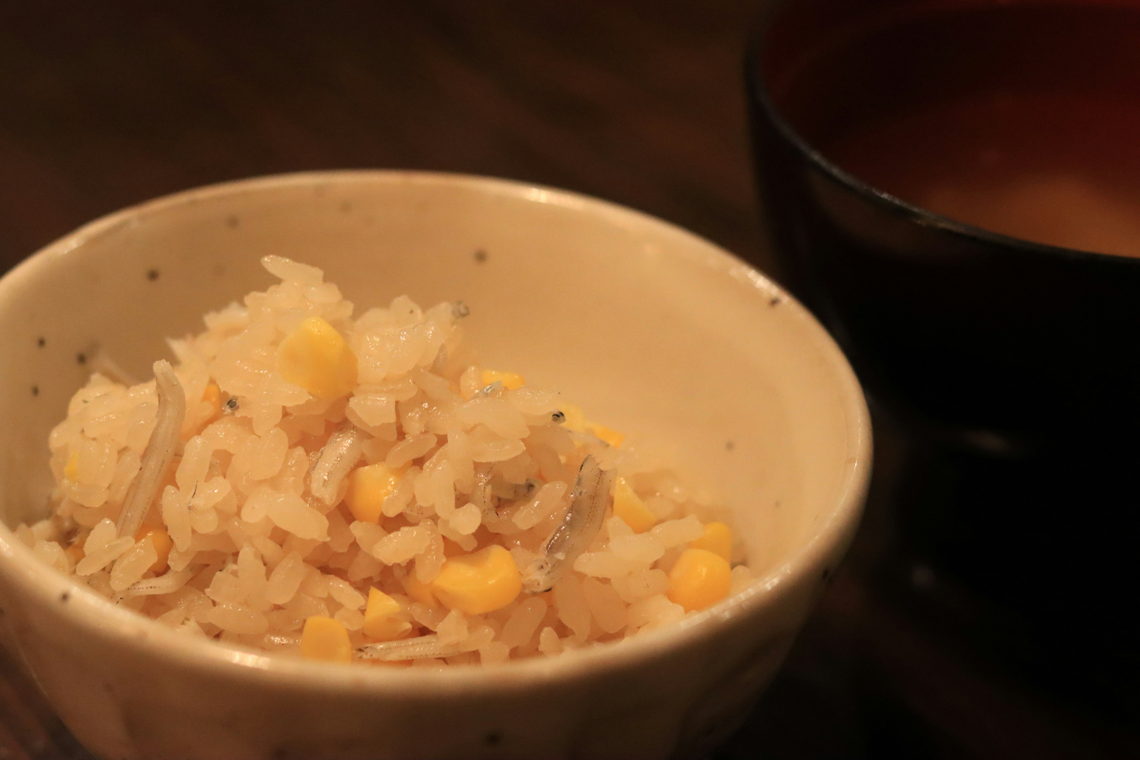 Bowl of rice mixed with corn alongside a bowl of miso soup