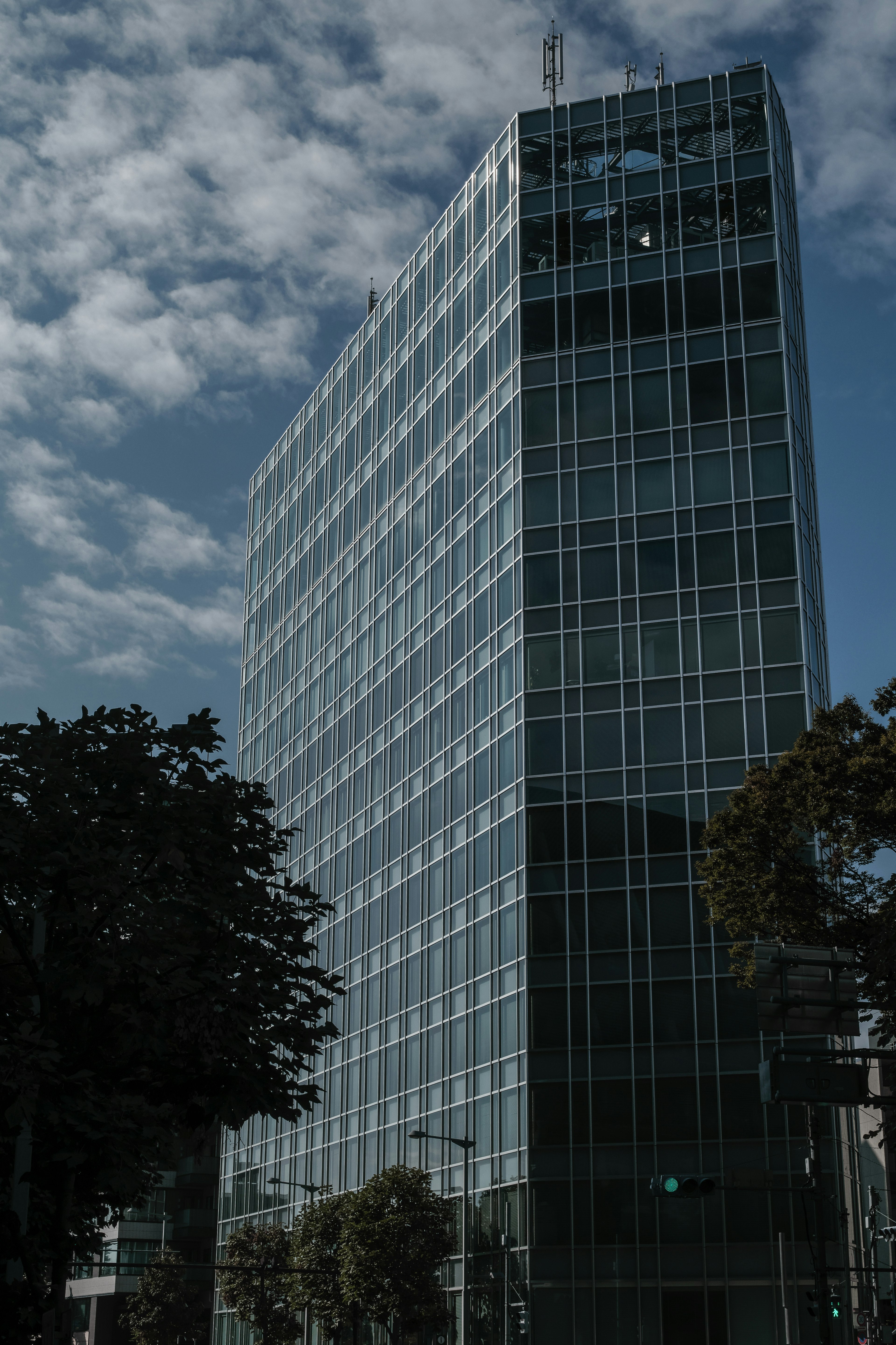 Modern glass skyscraper with a cloudy sky background