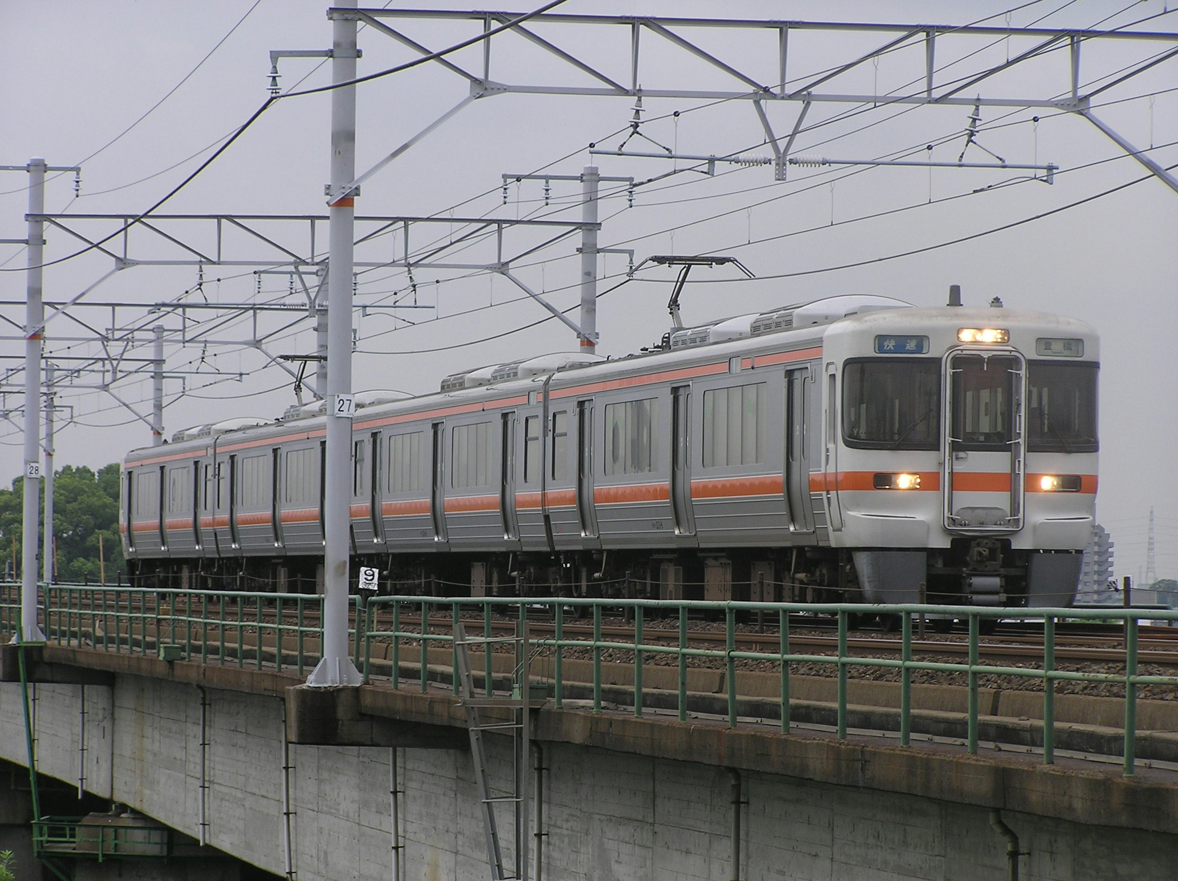 火車穿越橋樑，上方有電力線