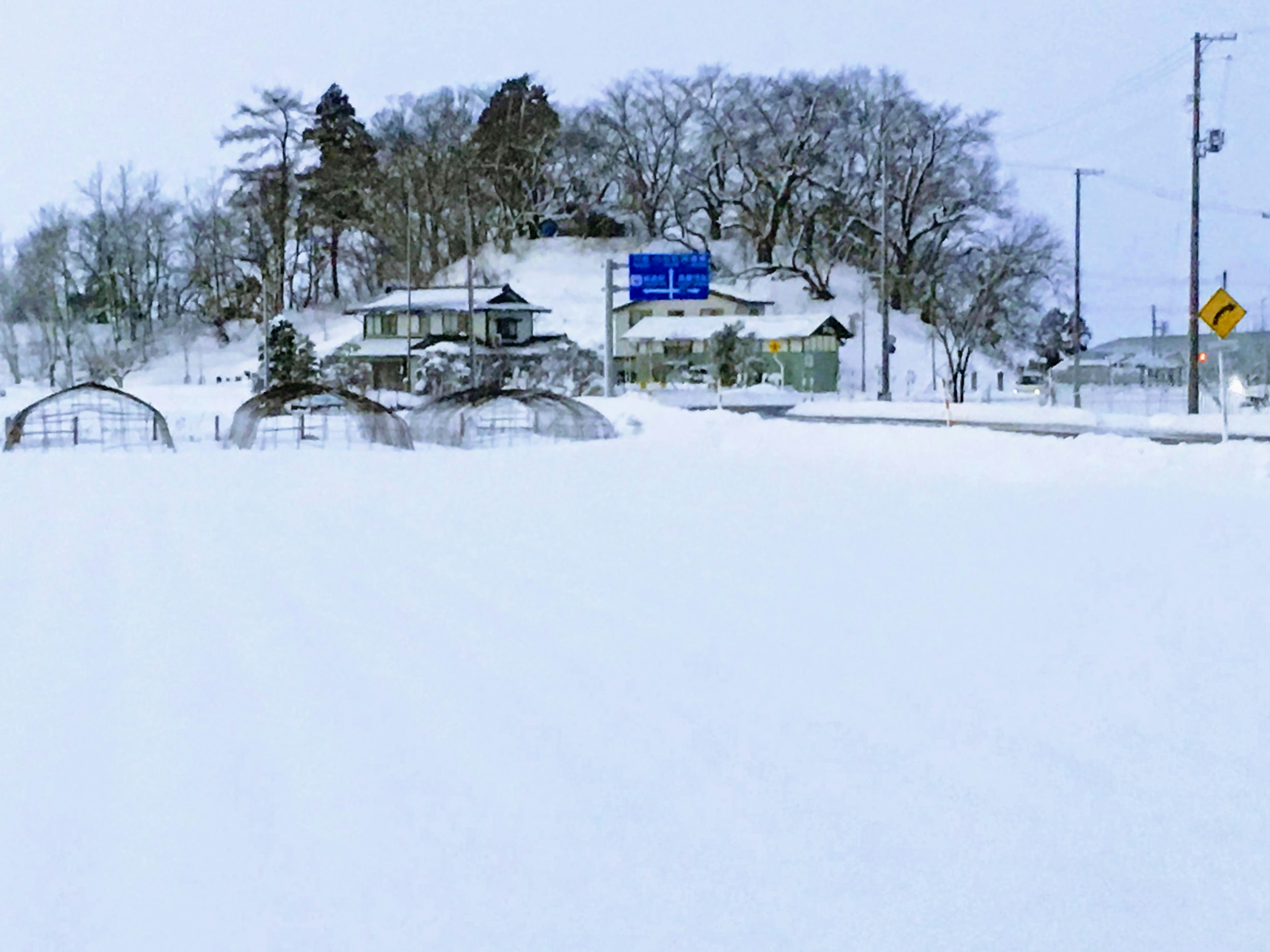 Paisaje cubierto de nieve con una casa y señales de tráfico