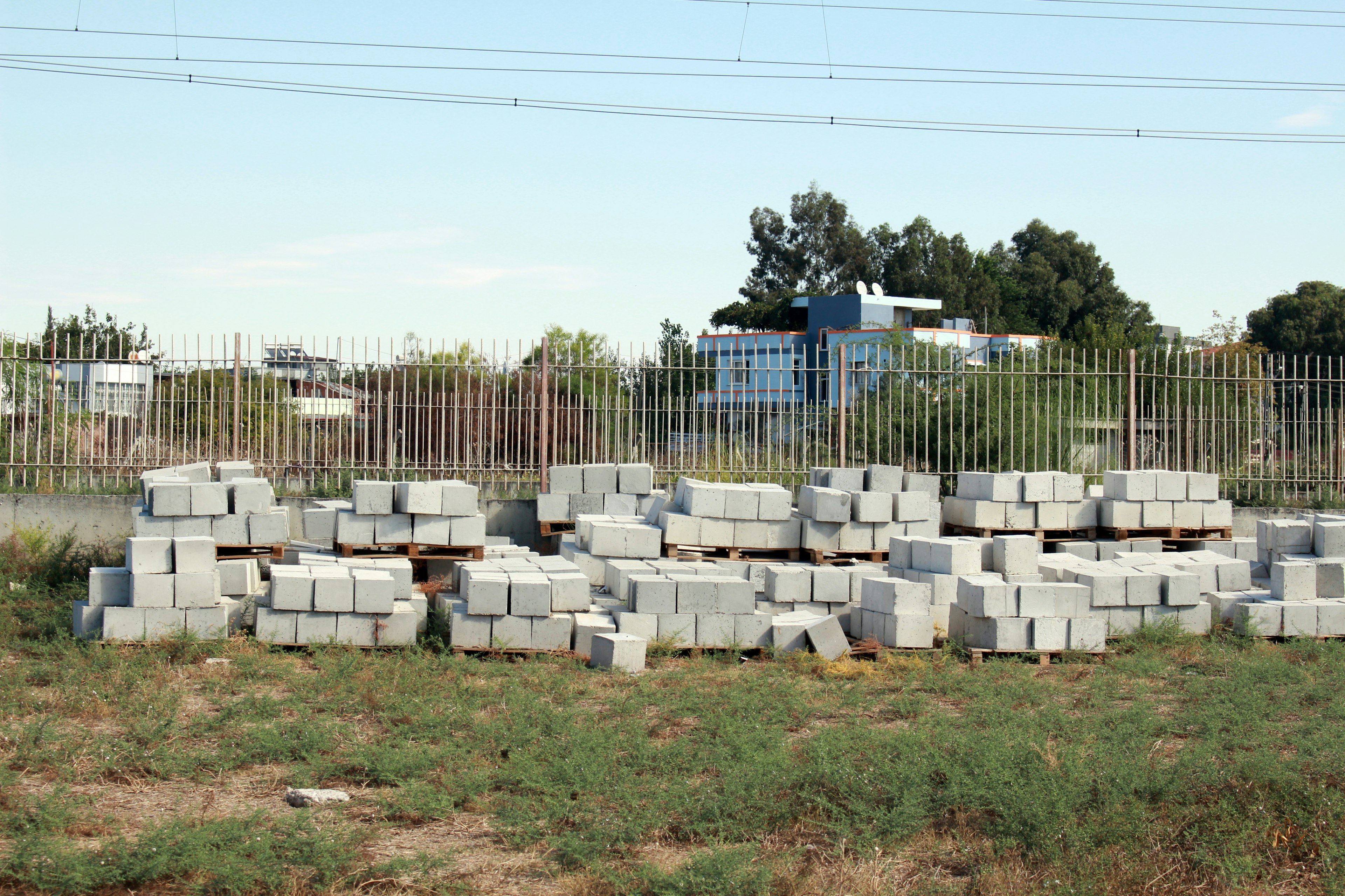 Bloques de concreto apilados en un sitio de construcción con una cerca al fondo