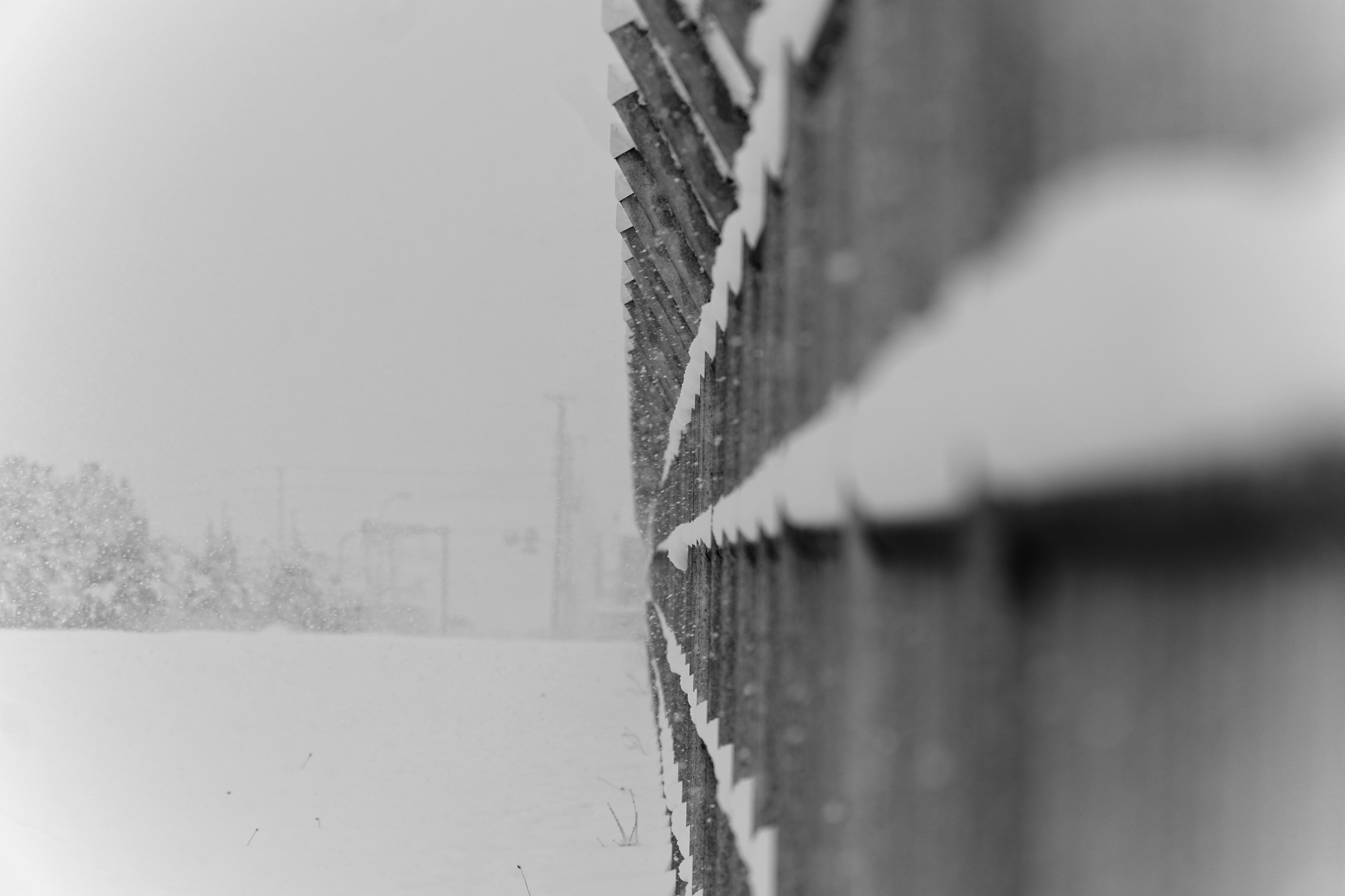 Snow-covered wooden fence with blurred building in the background