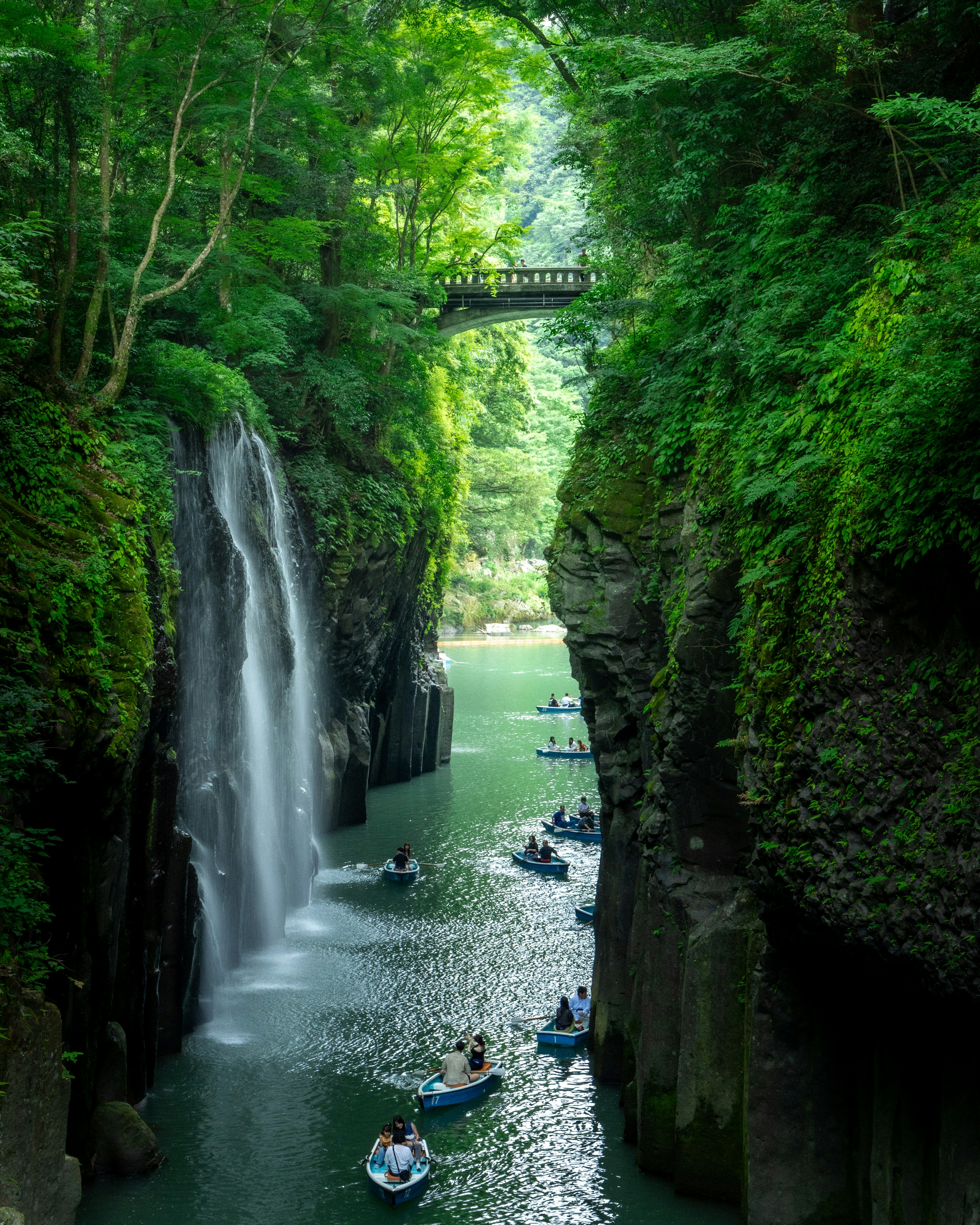 美丽的风景，瀑布倾泻入绿色峡谷，船只漂浮