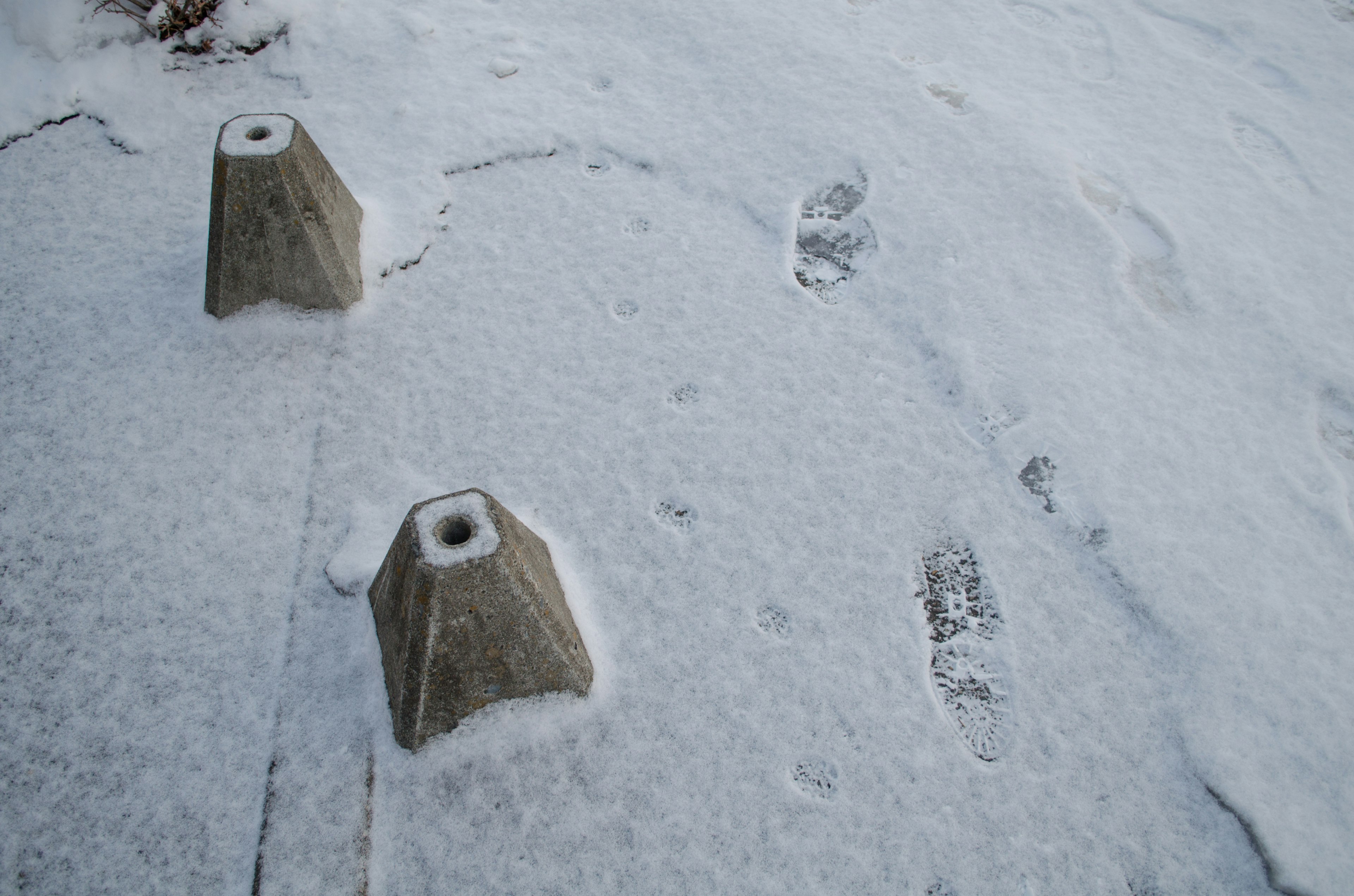 雪に覆われた地面にあるコンクリートの障害物と足跡