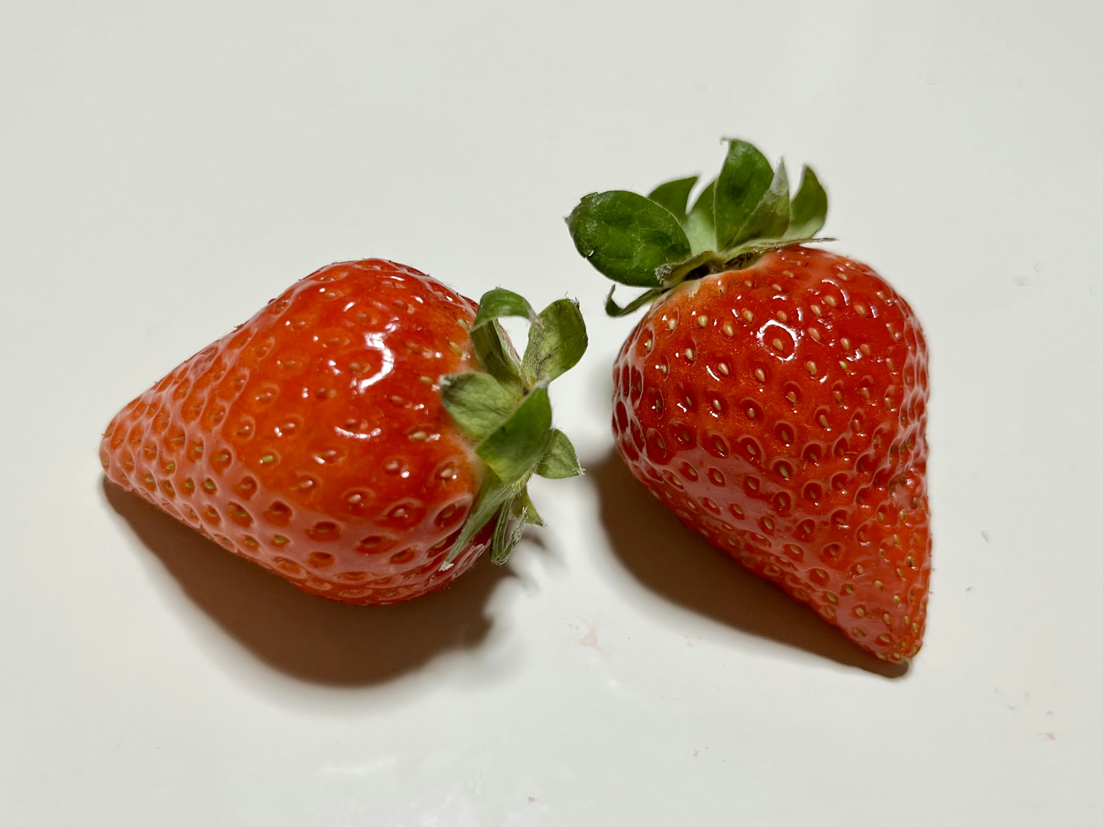 Two fresh strawberries placed on a white plate