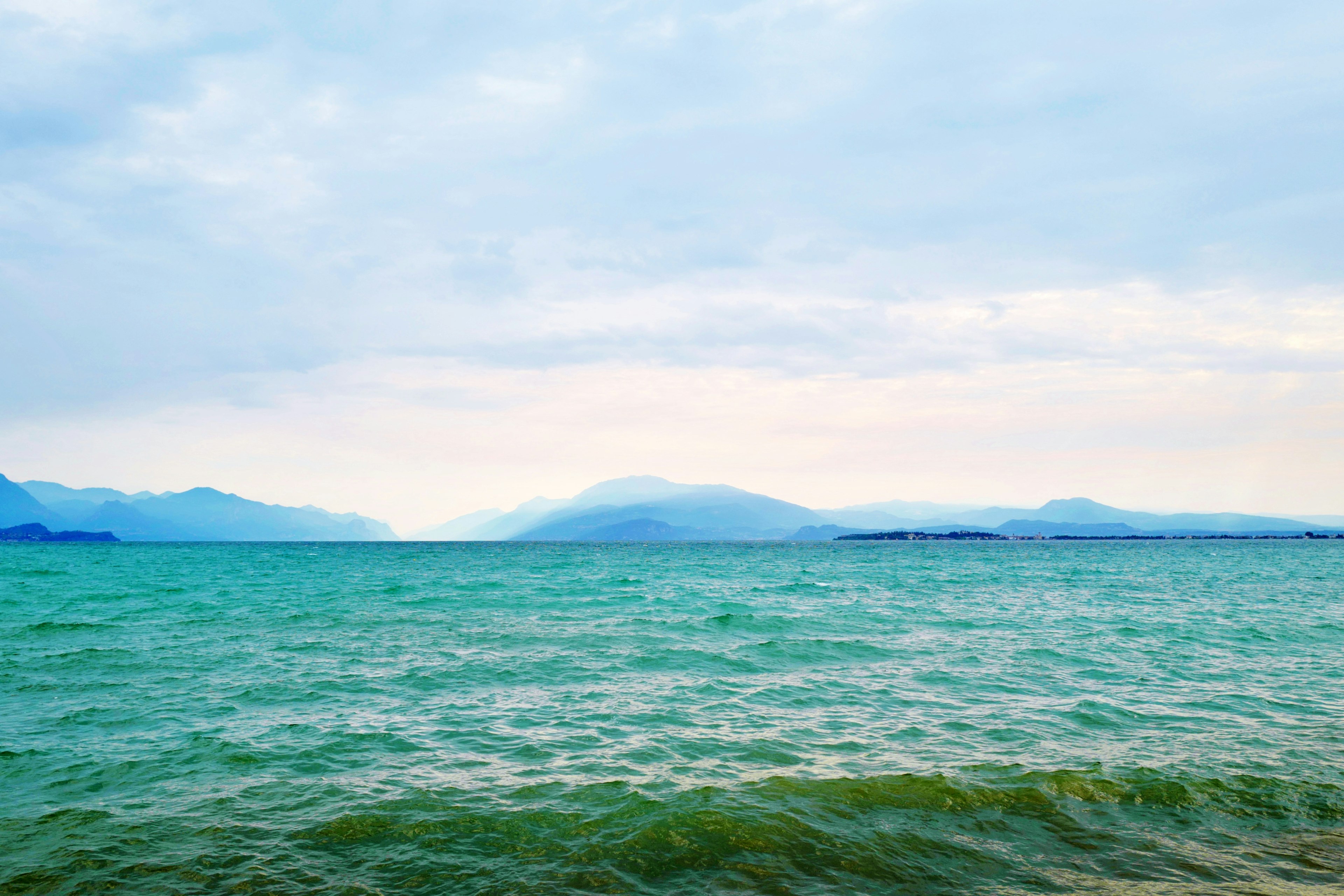 Vasto mare blu con onde leggere sotto un cielo nuvoloso