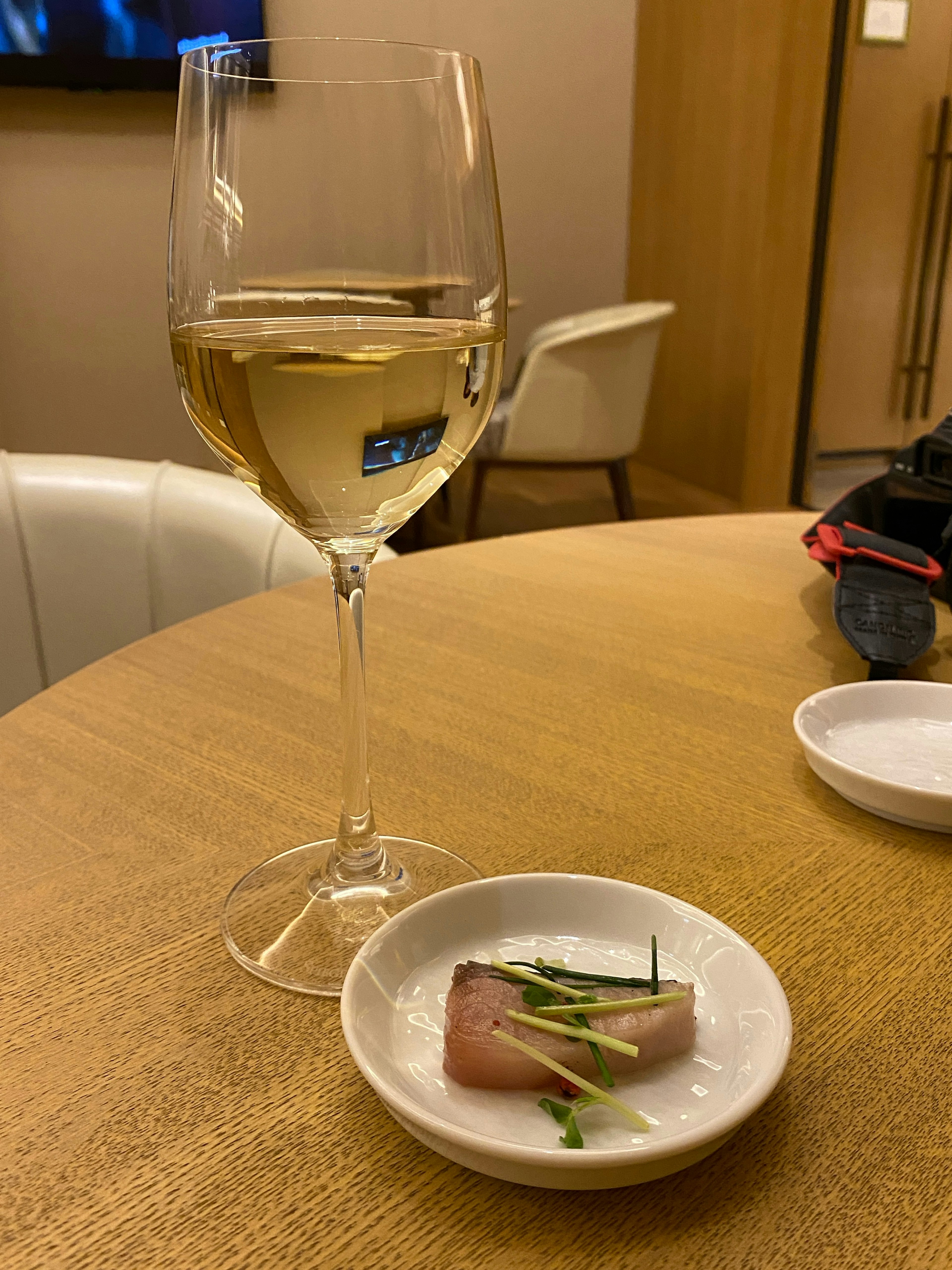 Imagen de una copa de vino blanco y sashimi en un plato pequeño