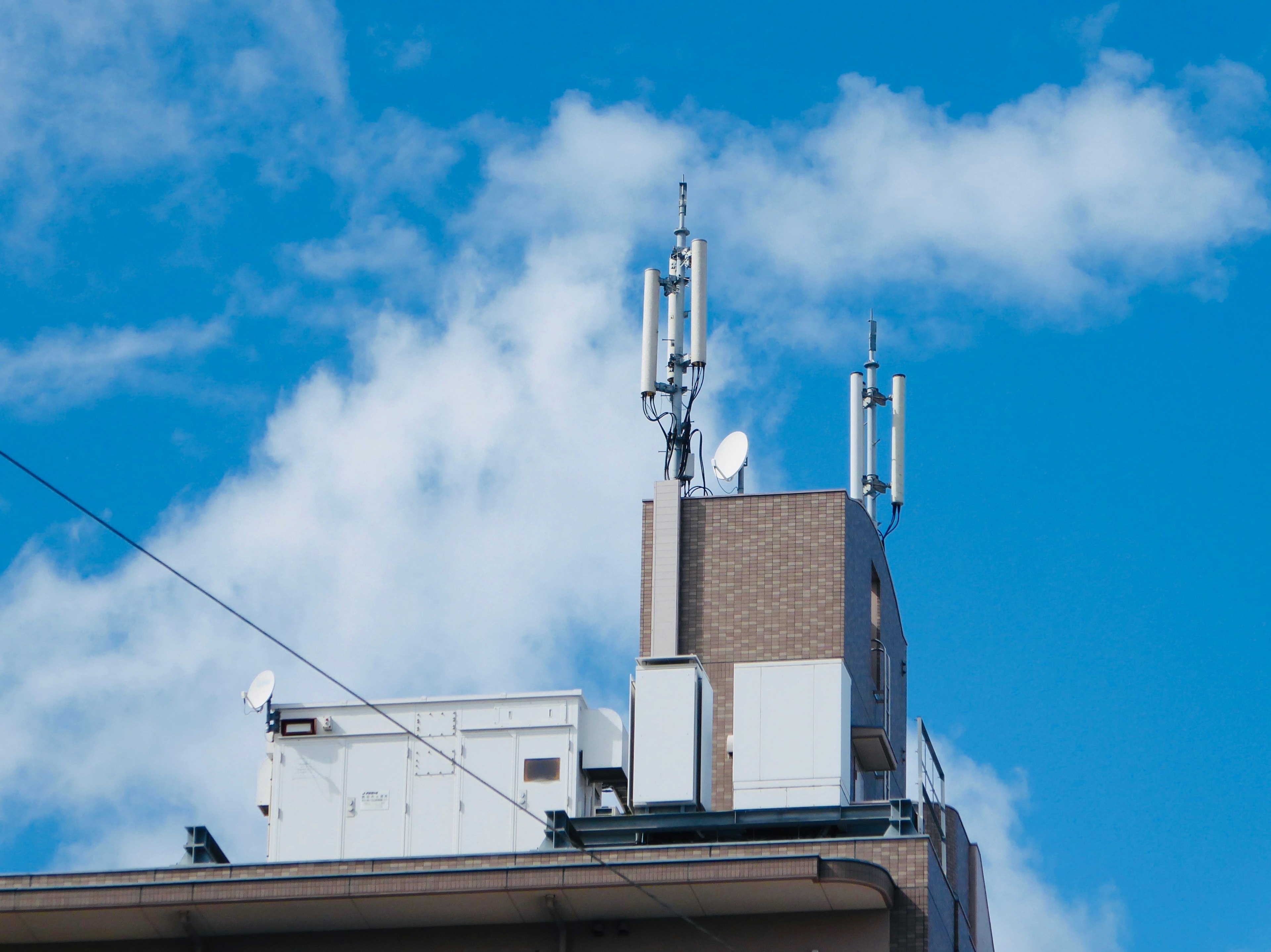 Communication antennas on a building rooftop under a blue sky