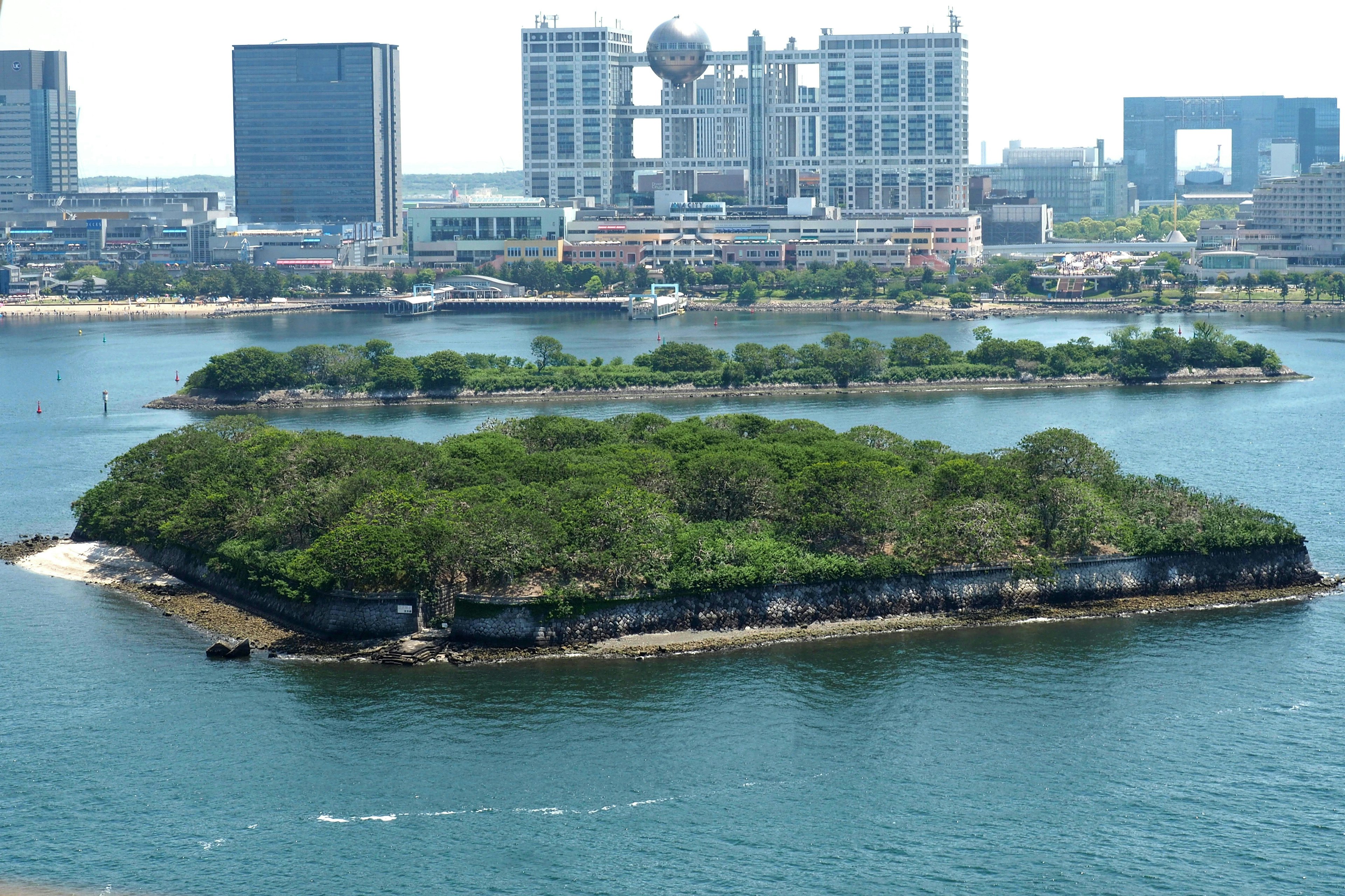 Isola verdeggiante circondata da acqua blu con skyline cittadino sullo sfondo