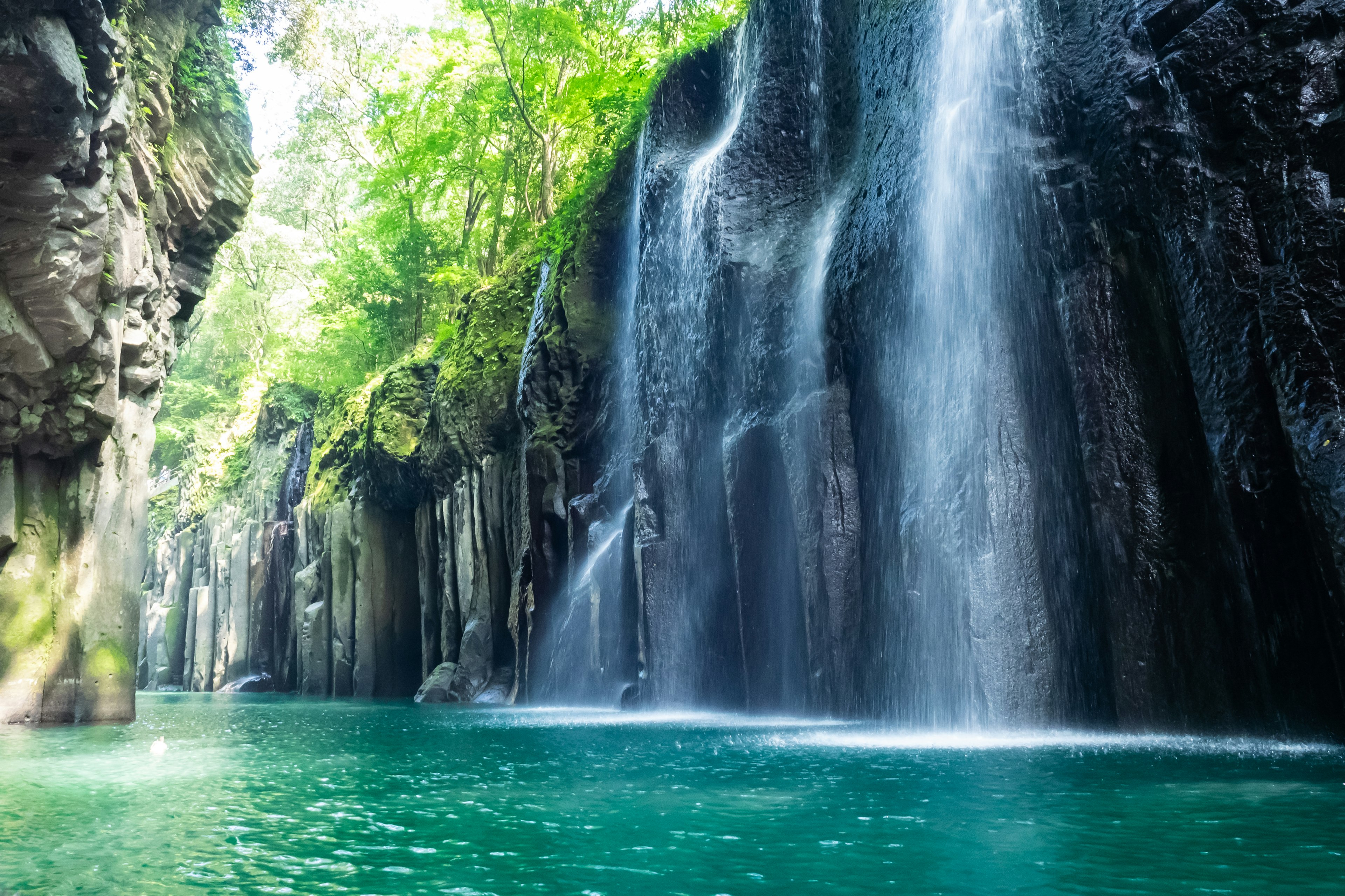 Majestuosa cascada rodeada de árboles verdes exuberantes y agua turquesa